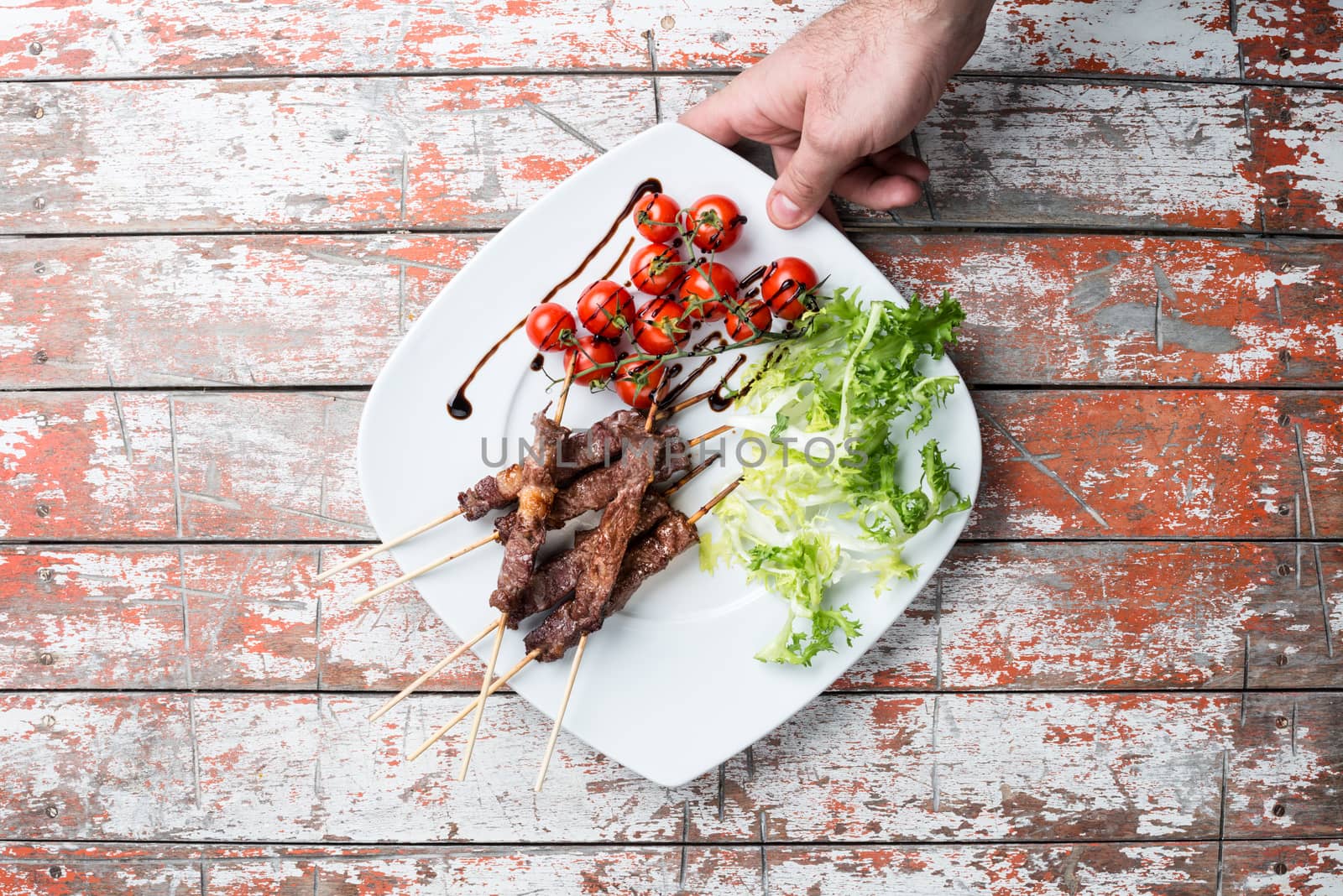 Arrosticini meat in a dish with salad and tomatoes on the table