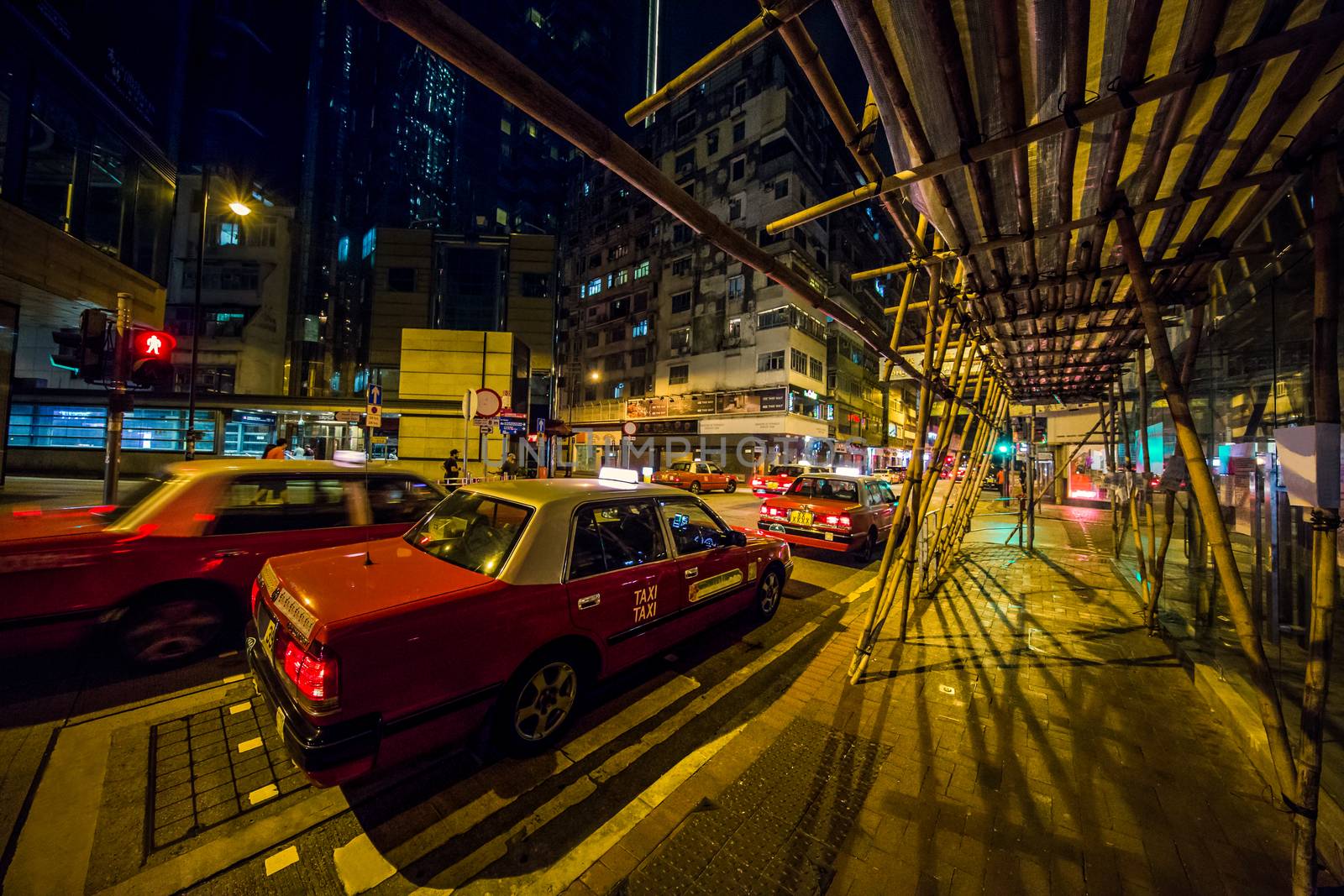 Red taxis at late night at an intersection in Hong Kong by Obmeetsworld