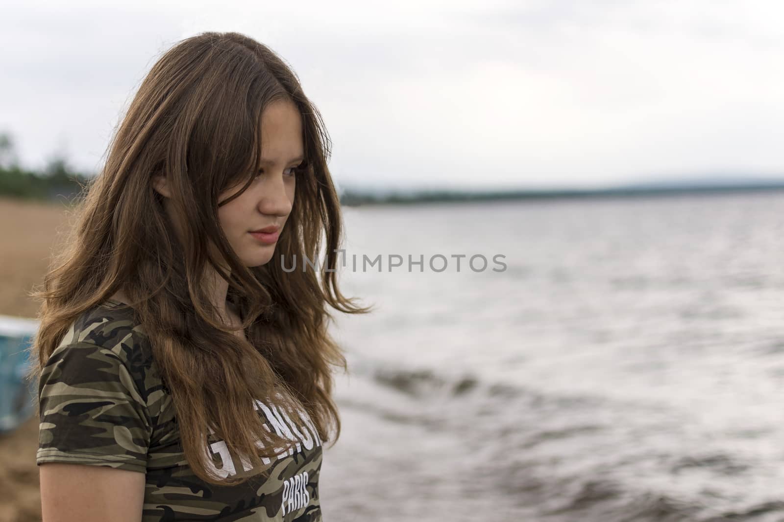 A young caucasian white woman sitting on a beach watching at the water