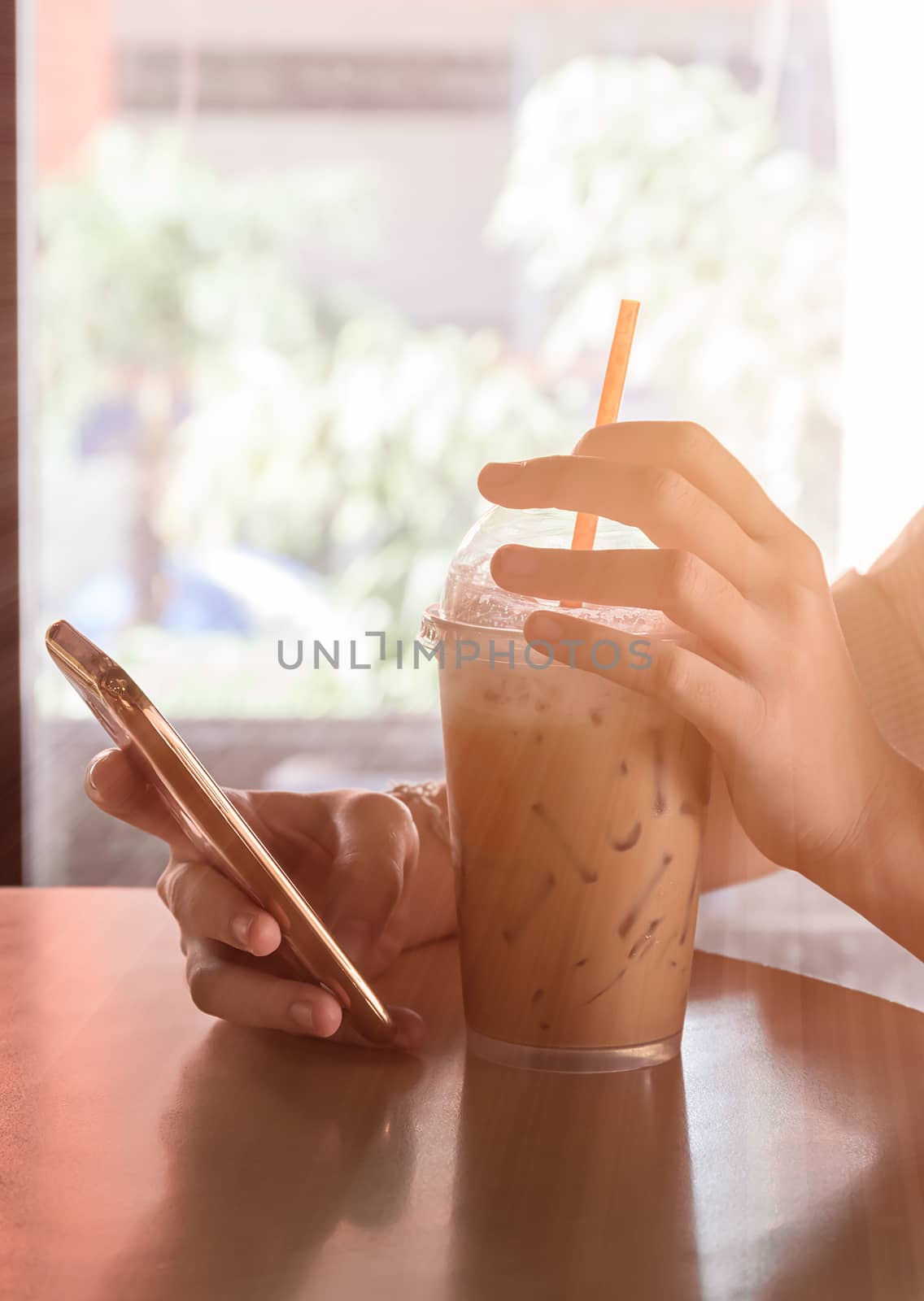 Hand woman using smartphone in coffee shop and a cup of coffee on the table with soft light vintage filter