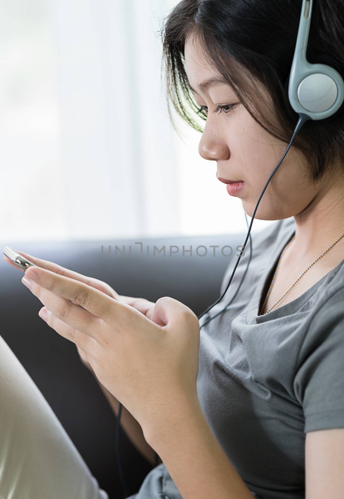 Close up young asian woman short hair listening music from mobile phone on the couch