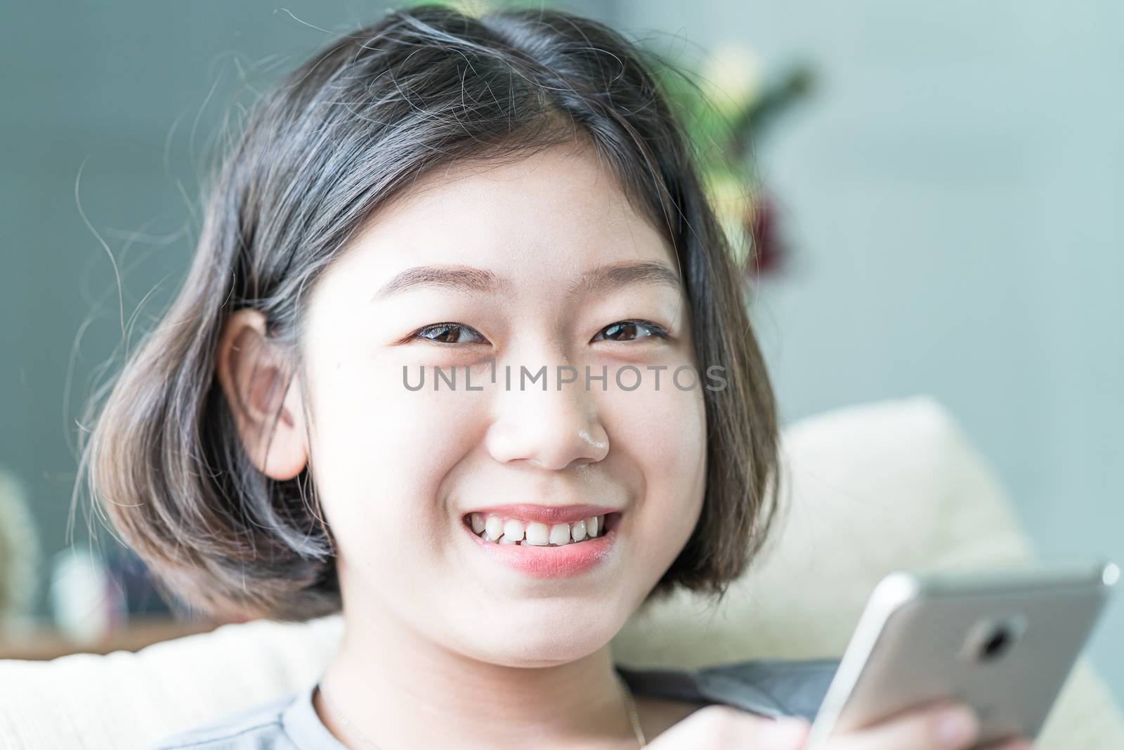 Close up young asian woman short hair listening music from mobile phone on the couch