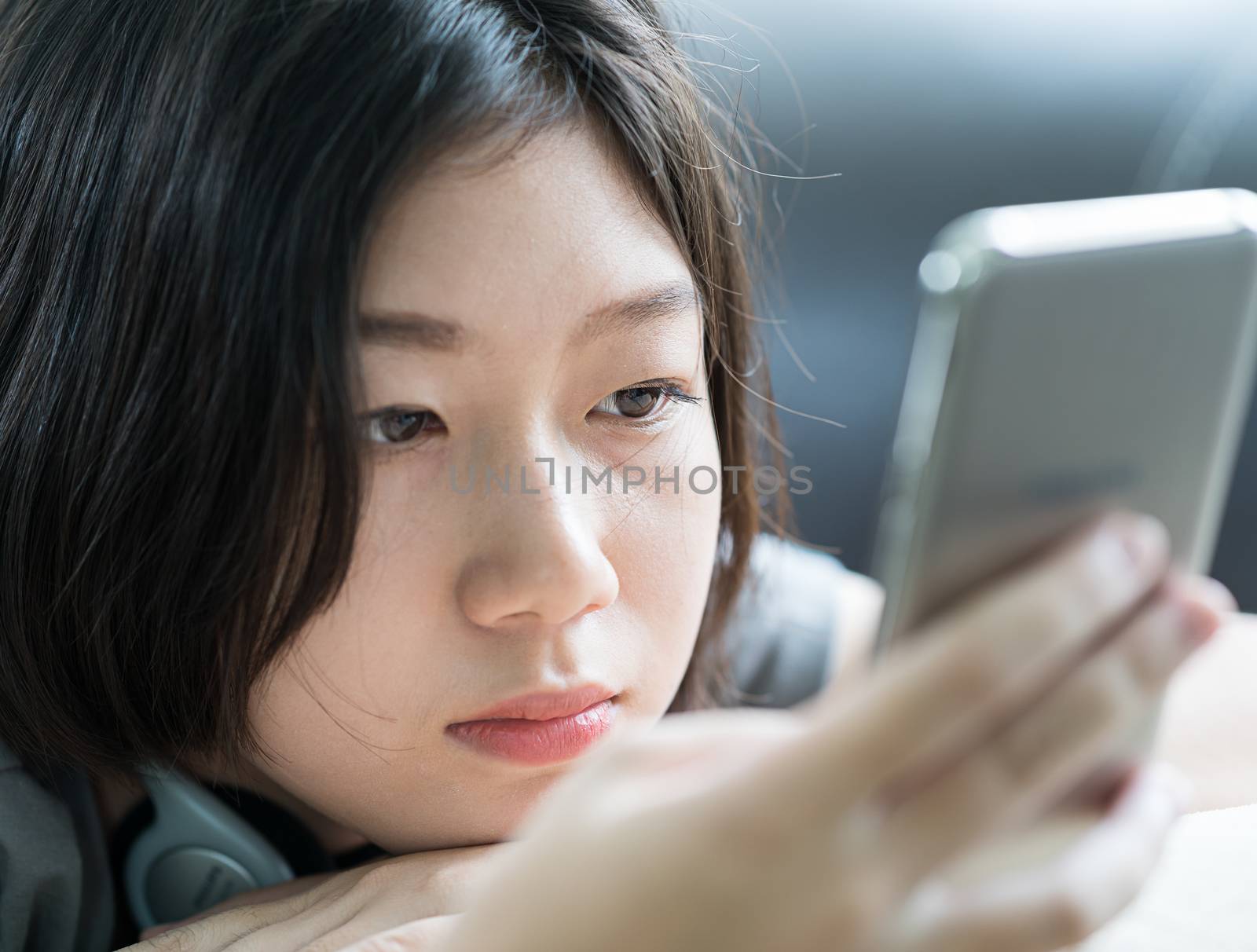 Close up young asian woman short hair listening music from mobile phone on the couch