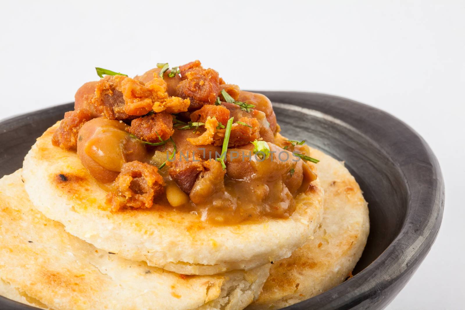 Traditional Colombian arepa topped with beans and pork rind