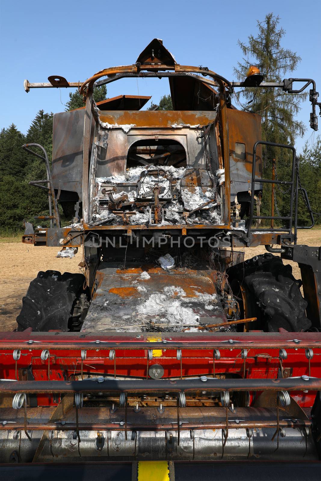 Burnt out combine harvester in field - front view