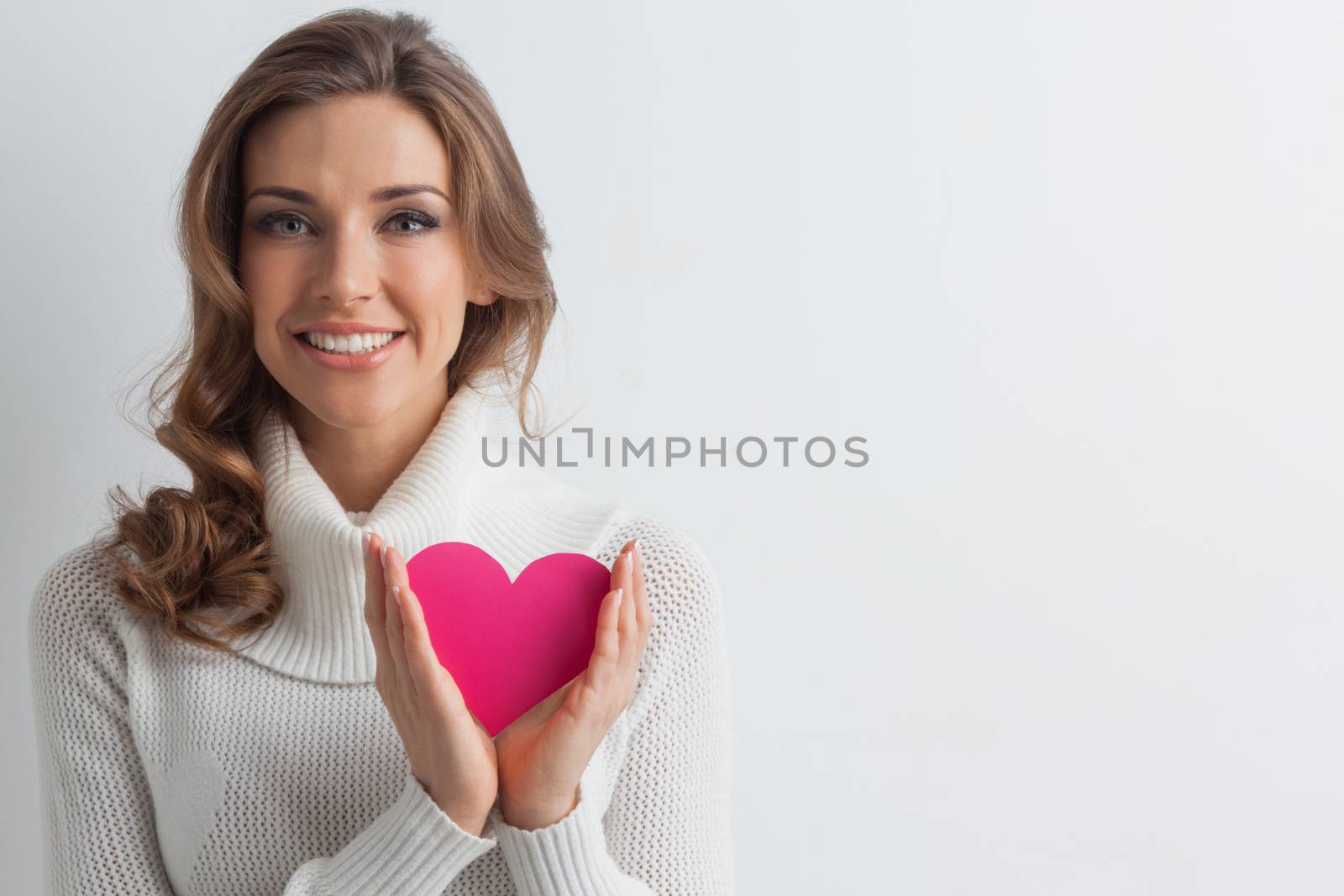 Happy young smiling woman with pink paper heart