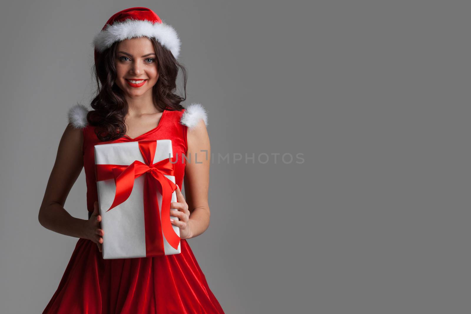 Beautiful woman in Santa Claus style dress with gift box