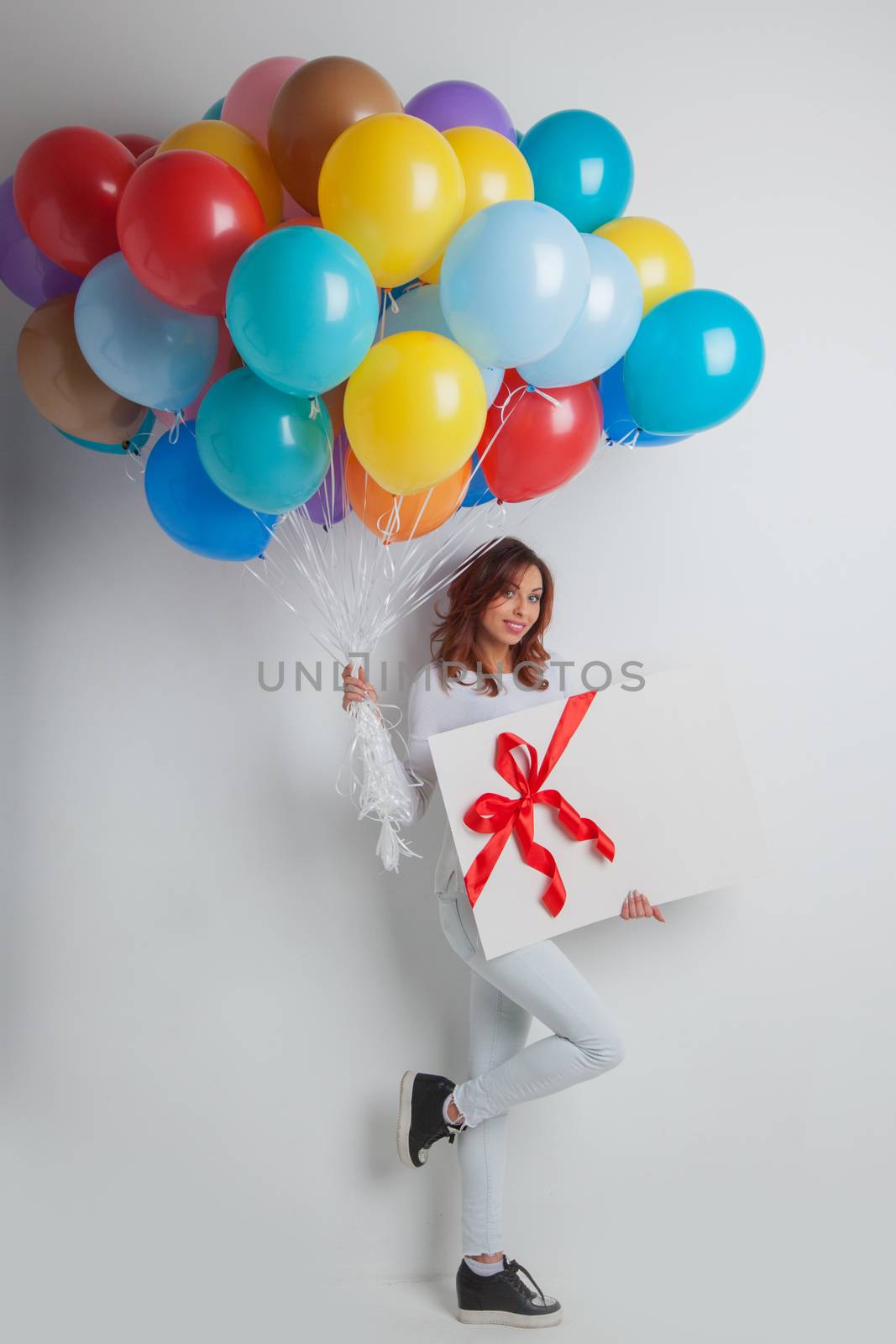 Happy woman with many colorful balloons and gift box