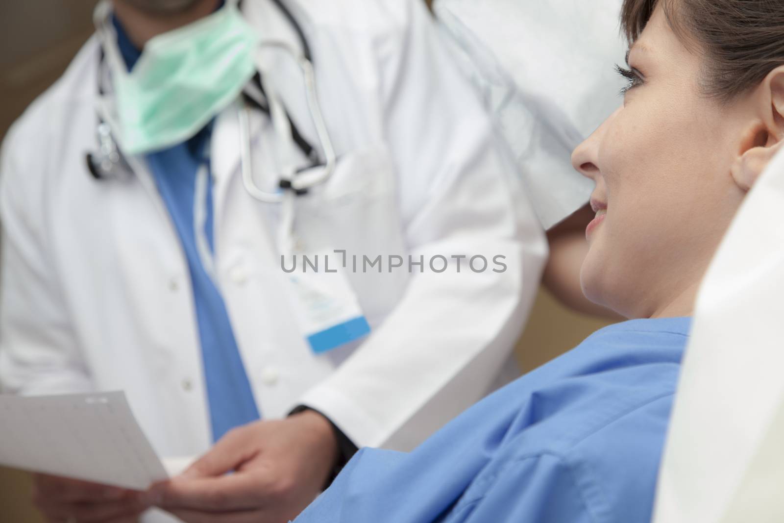 A smiling pretty female patient is listening to her diagnosis held by a doctor, torso only, blurred in background.