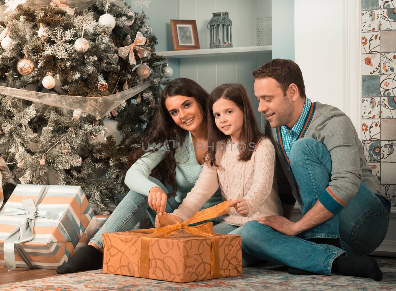 Happy family gather near Christmas tree with presents