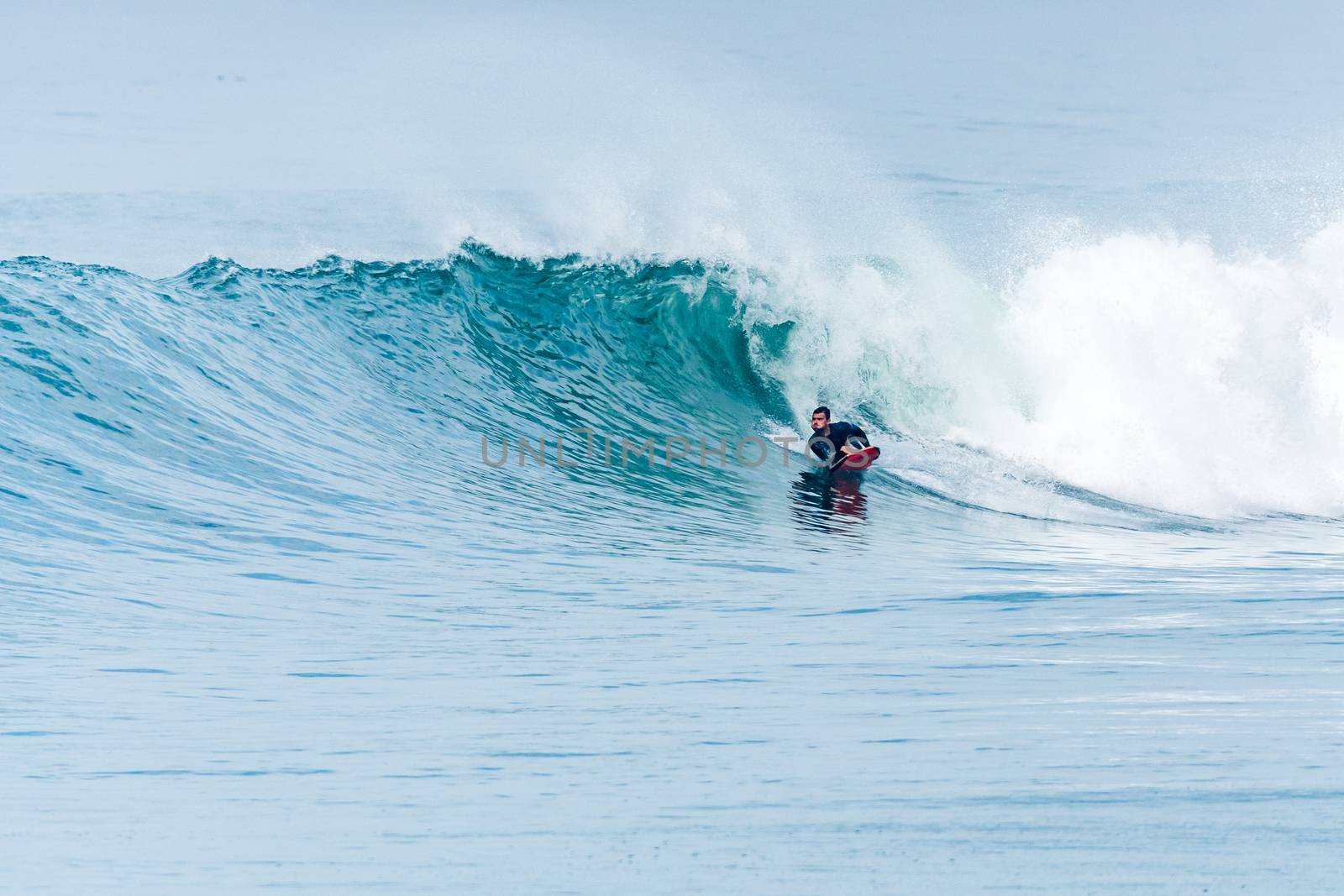 Bodyboarder surfing ocean wave on a sunny day.