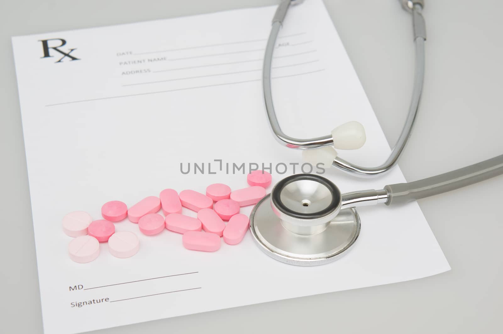 Close up old silver medical stethoscope and pink pills place on blur rx prescription form as background with white table and copy space. Healthcare and medical concept photography.