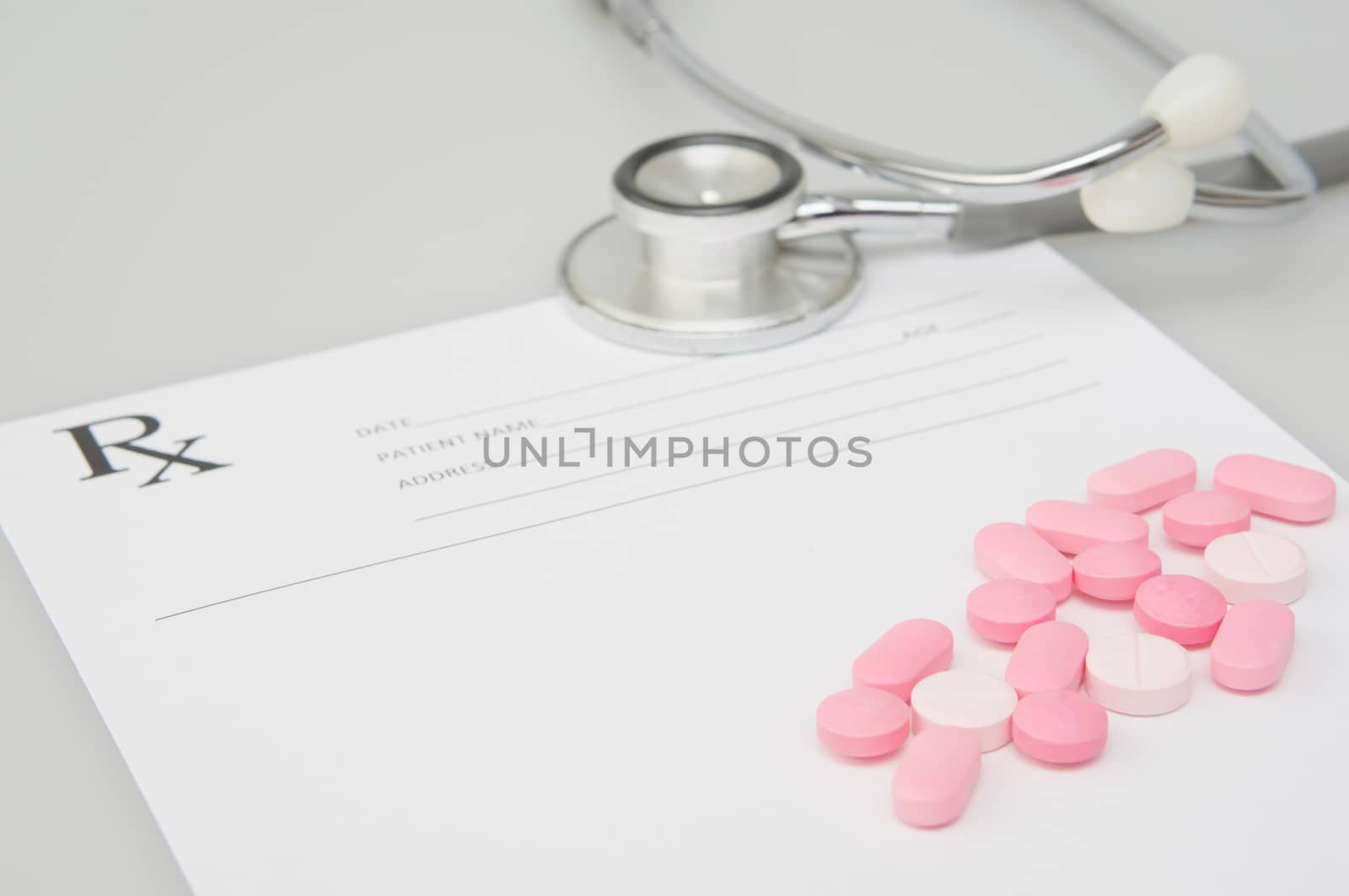 Close up pink pills on blur rx prescription form with old silver medical stethoscope on white background and copy space. Healthcare and medical concept photography.