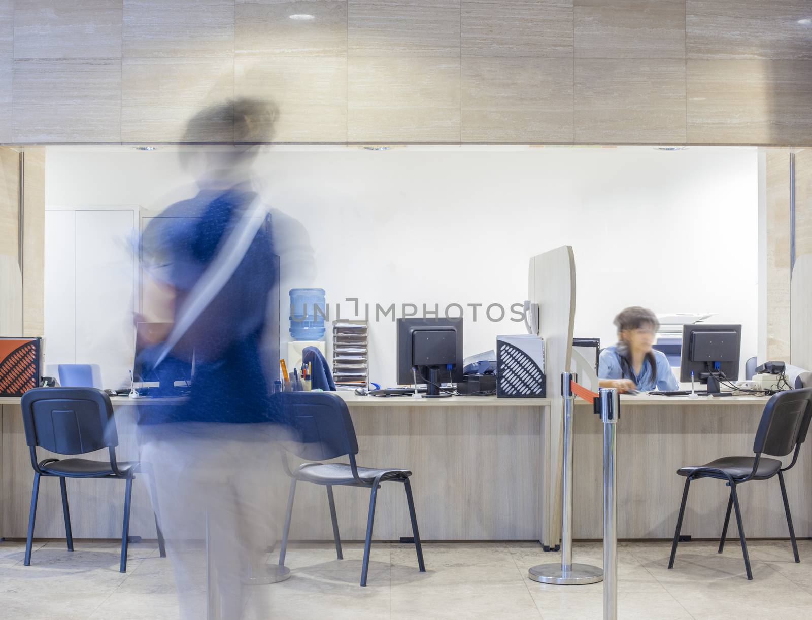 Three seats in front of a Bank, customs, office, hospital, etc. registration desk with blurred figures of a clerk and a customer.