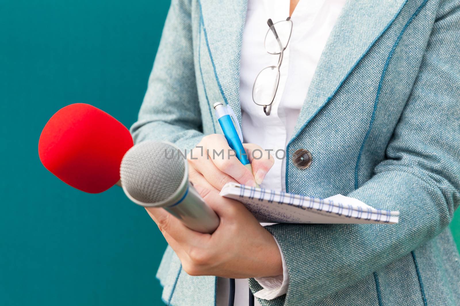 Female reporter taking notes at news conference. Journalism. by wellphoto