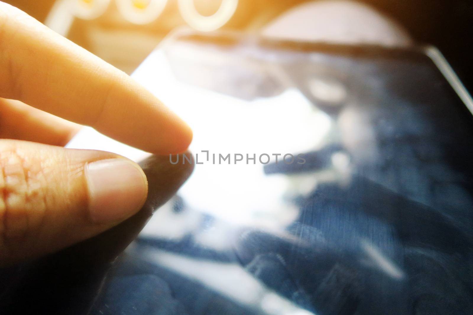 Close-up of female hands using digital tablet computer, hand presses on screen digital tablet with flare light background. Searching Internet ,Social Networking Concept