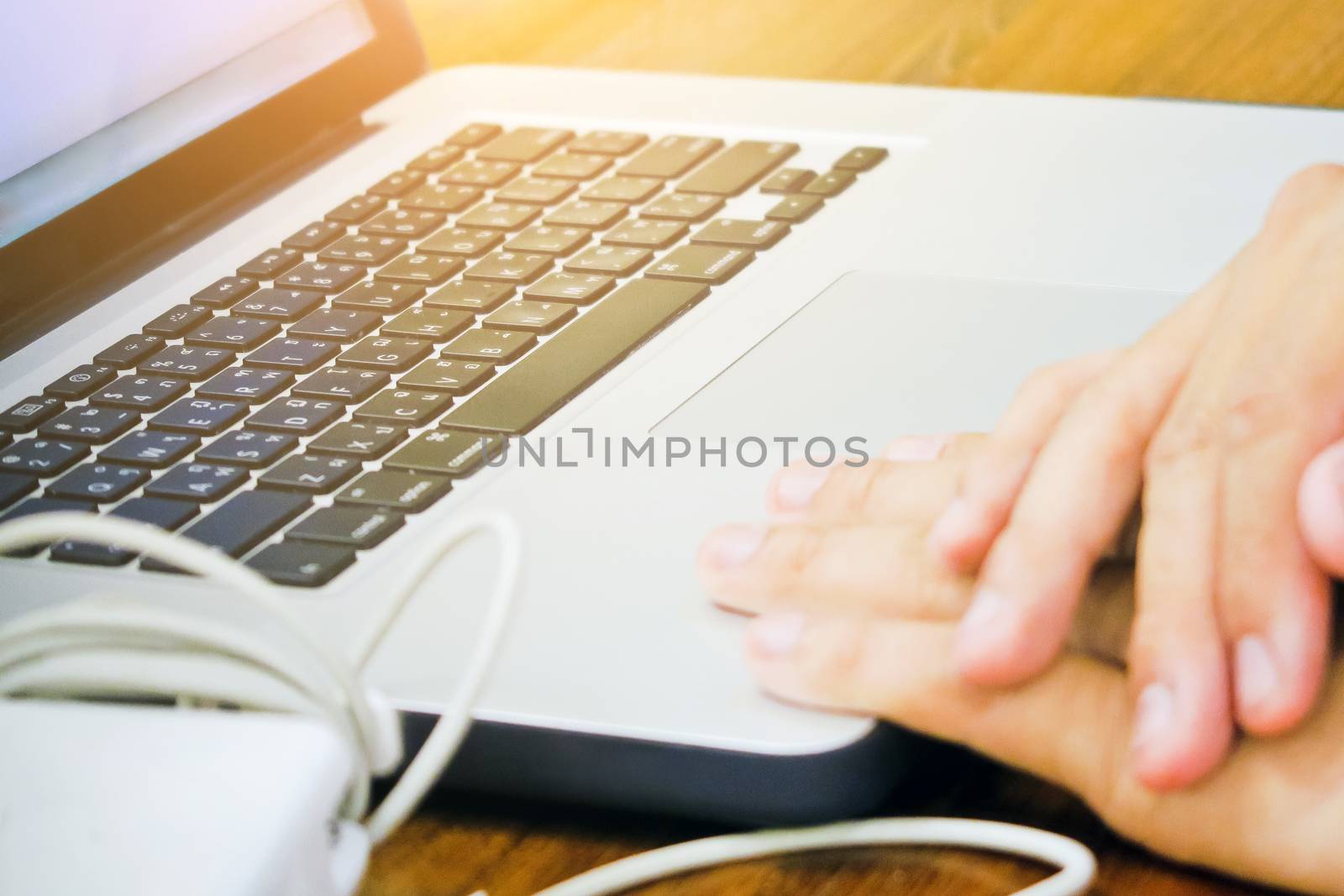 Close-up of female hands using laptop computer, working on laptop with flare light background. Searching Internet ,Social Networking Concept