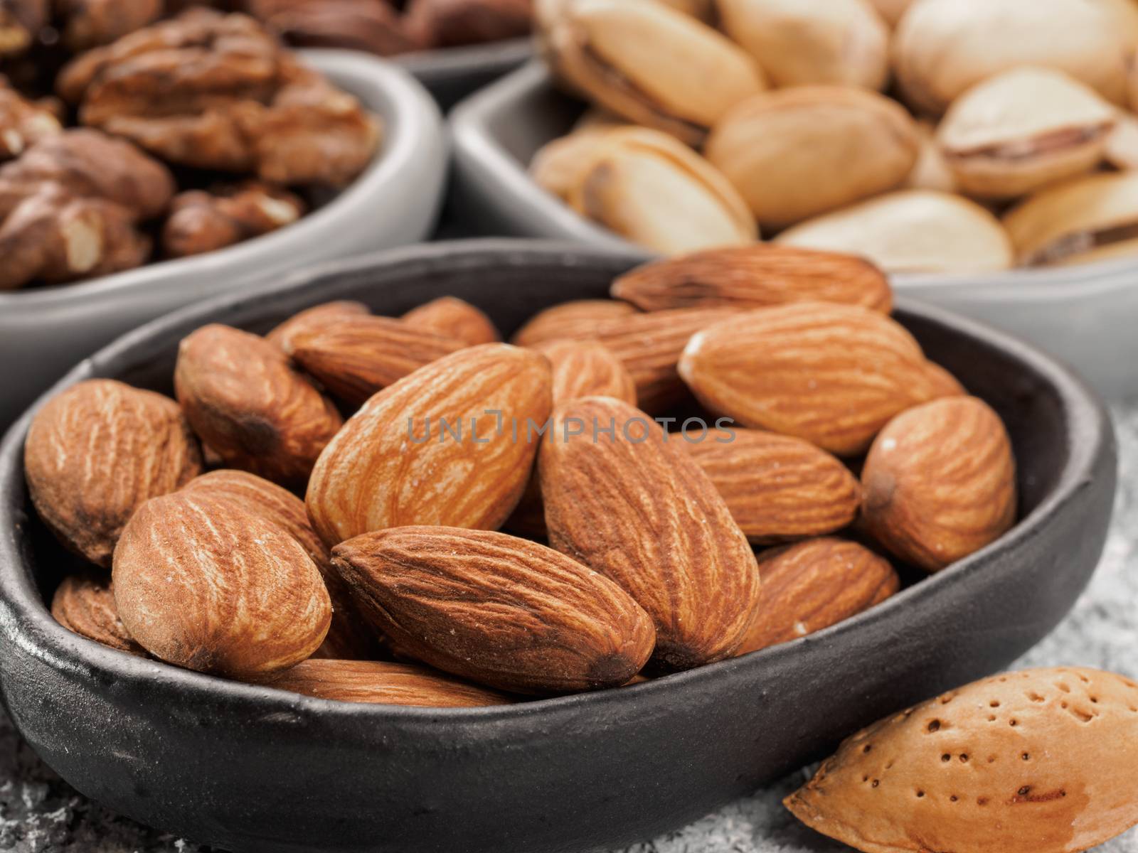 Almond in trendy plate close up on gray cement background.