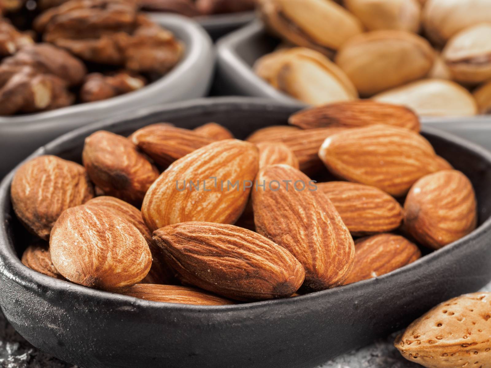 Almond in trendy plate close up on gray cement background.