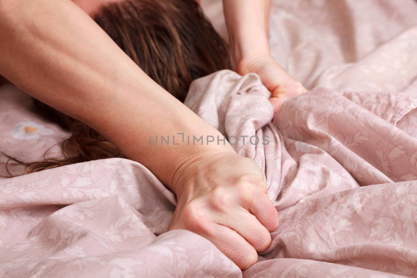 Closeup shot of hands of woman pulling the sheets in ecstasy, orgasm.