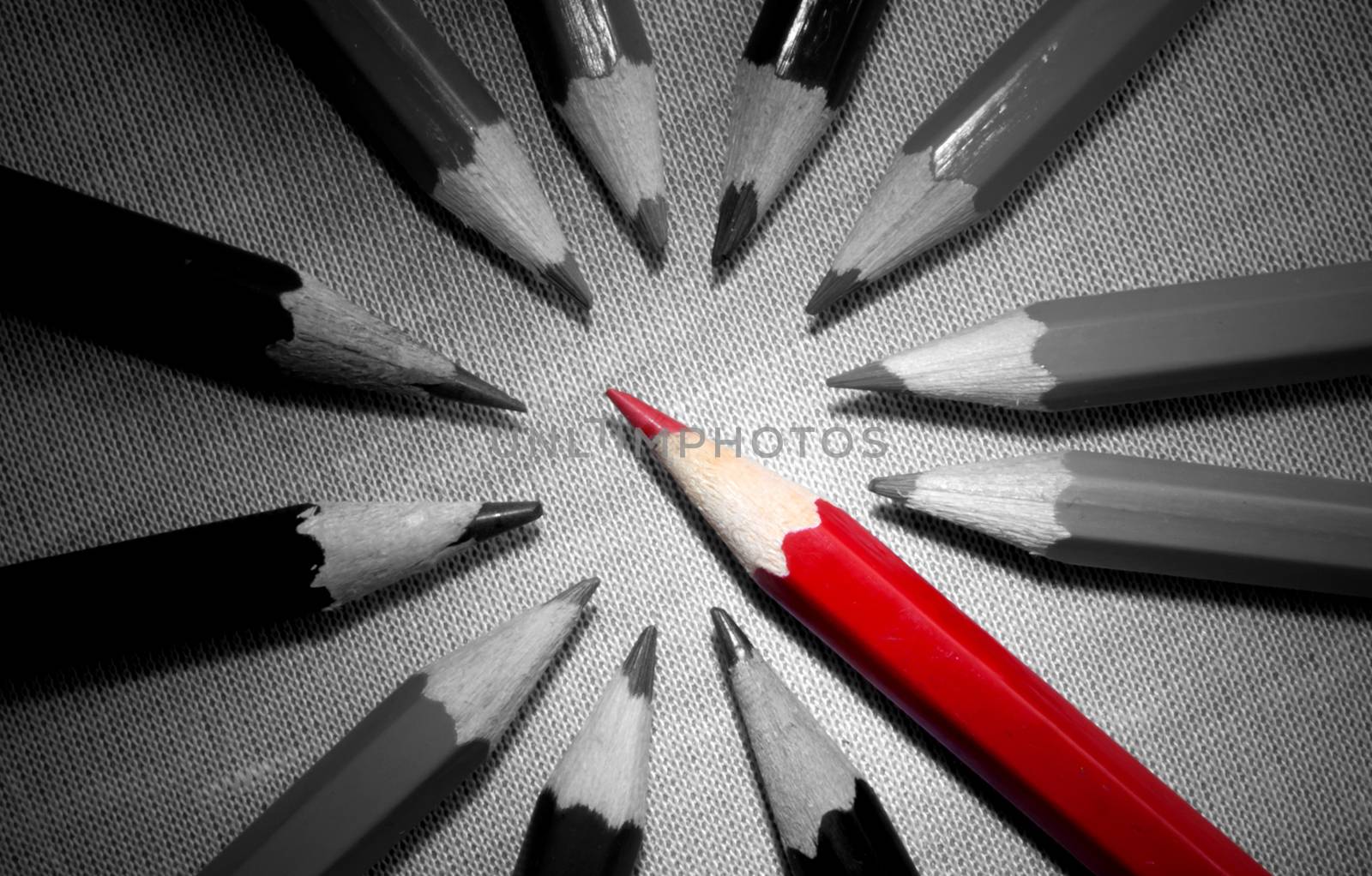 Red pencil standing out in a group of black and white pencils