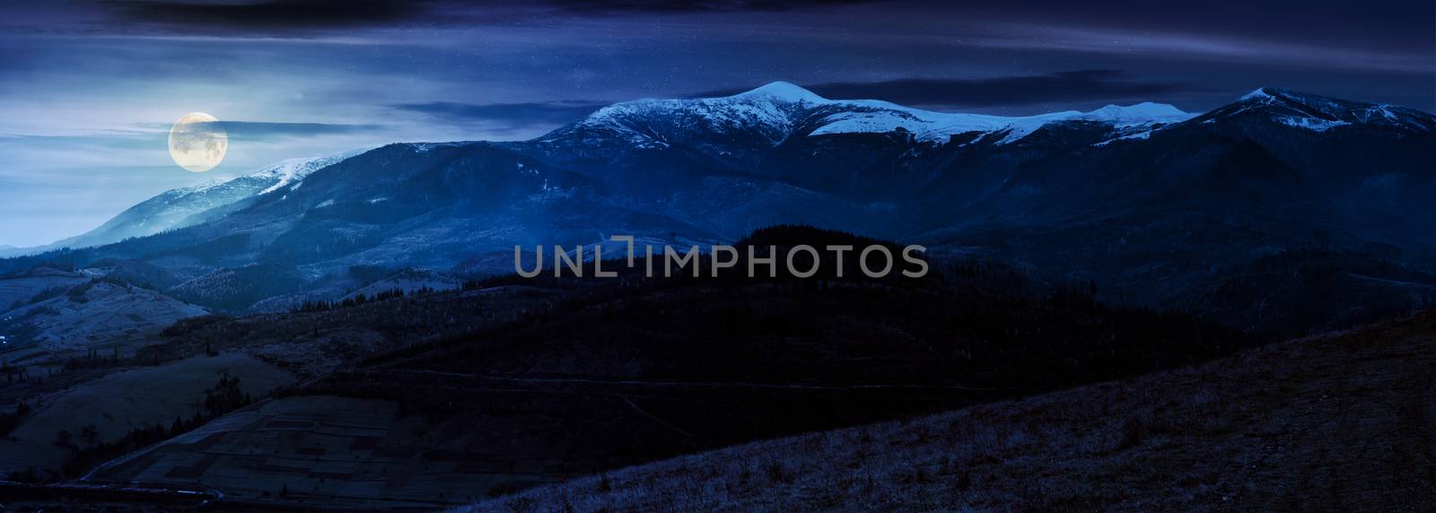 great mountain ridge Borzhava with snowy tops at night in full moon light. beautiful countryside landscape in late autumn