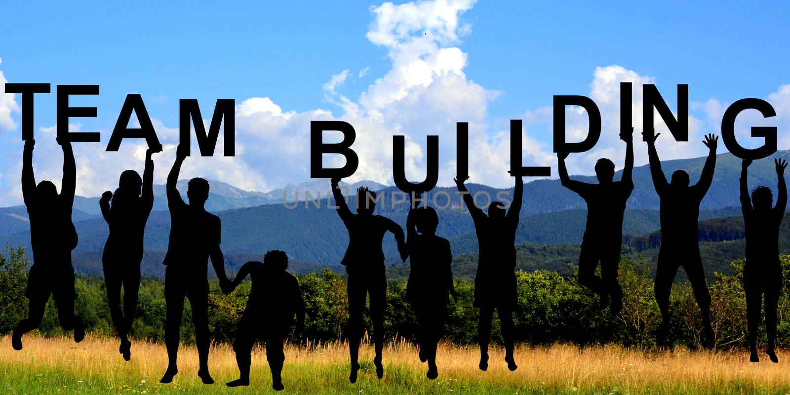 Silhouettes of people holding letters with TEAM BUILDING at mountains