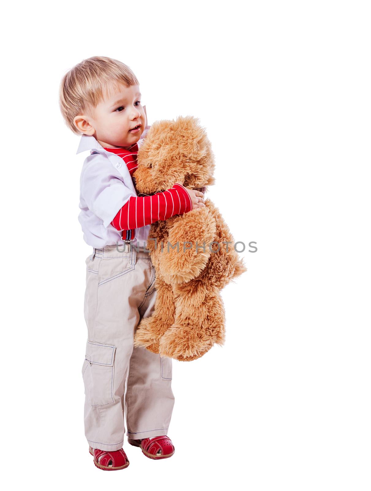 Little blond boy hugging bear toy standing isolated on white