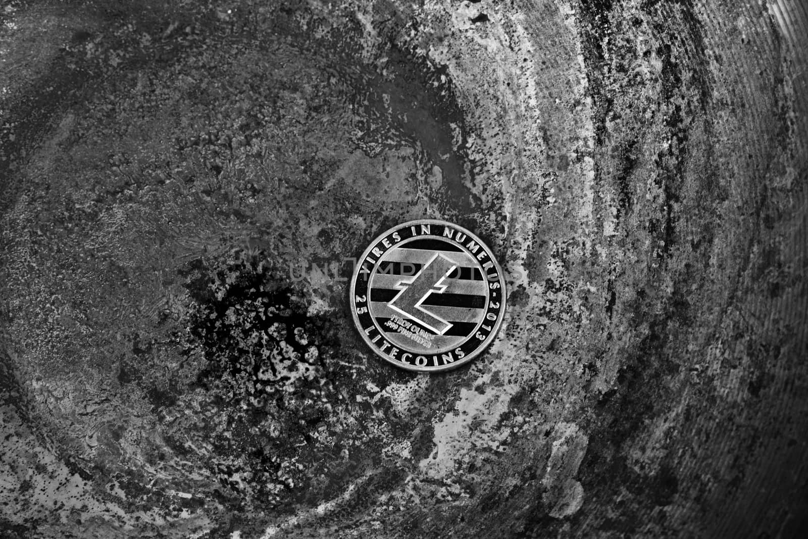 Crypto currency physical silver Litecoin coin on black dirty scene. Black and white concept.