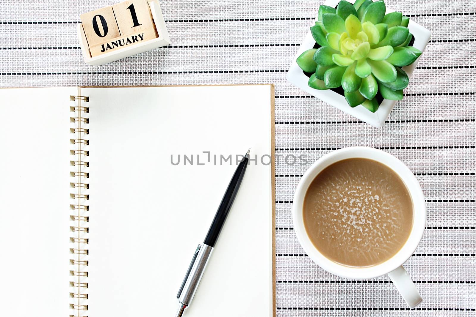 Top view or flat lay of open notebook paper, cube calendar and coffee cup on table background by sureeporn