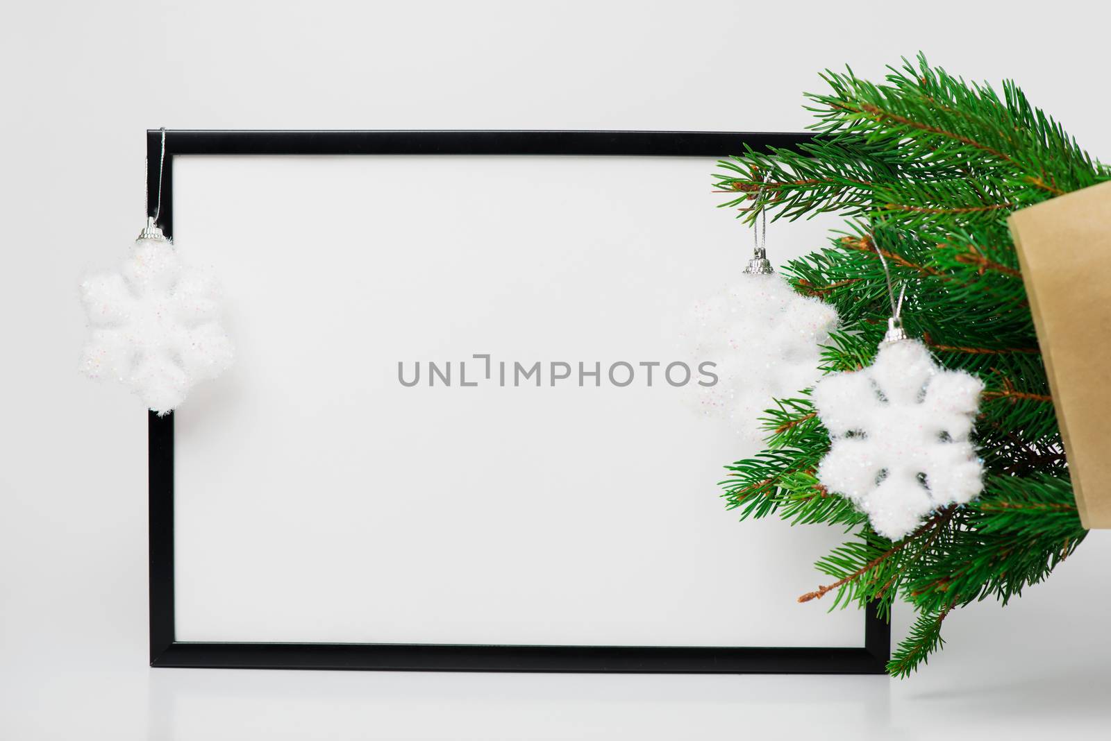Christmas composition. Black frame and  branches christmas tree, red balls on white background. Front view, mock up, copy space, square, flat lay, for congratulations

