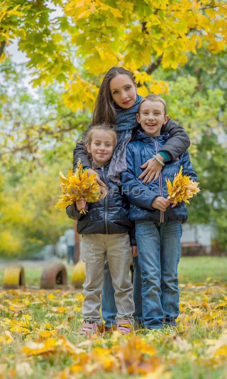 Mother hugging two children among autumn forest