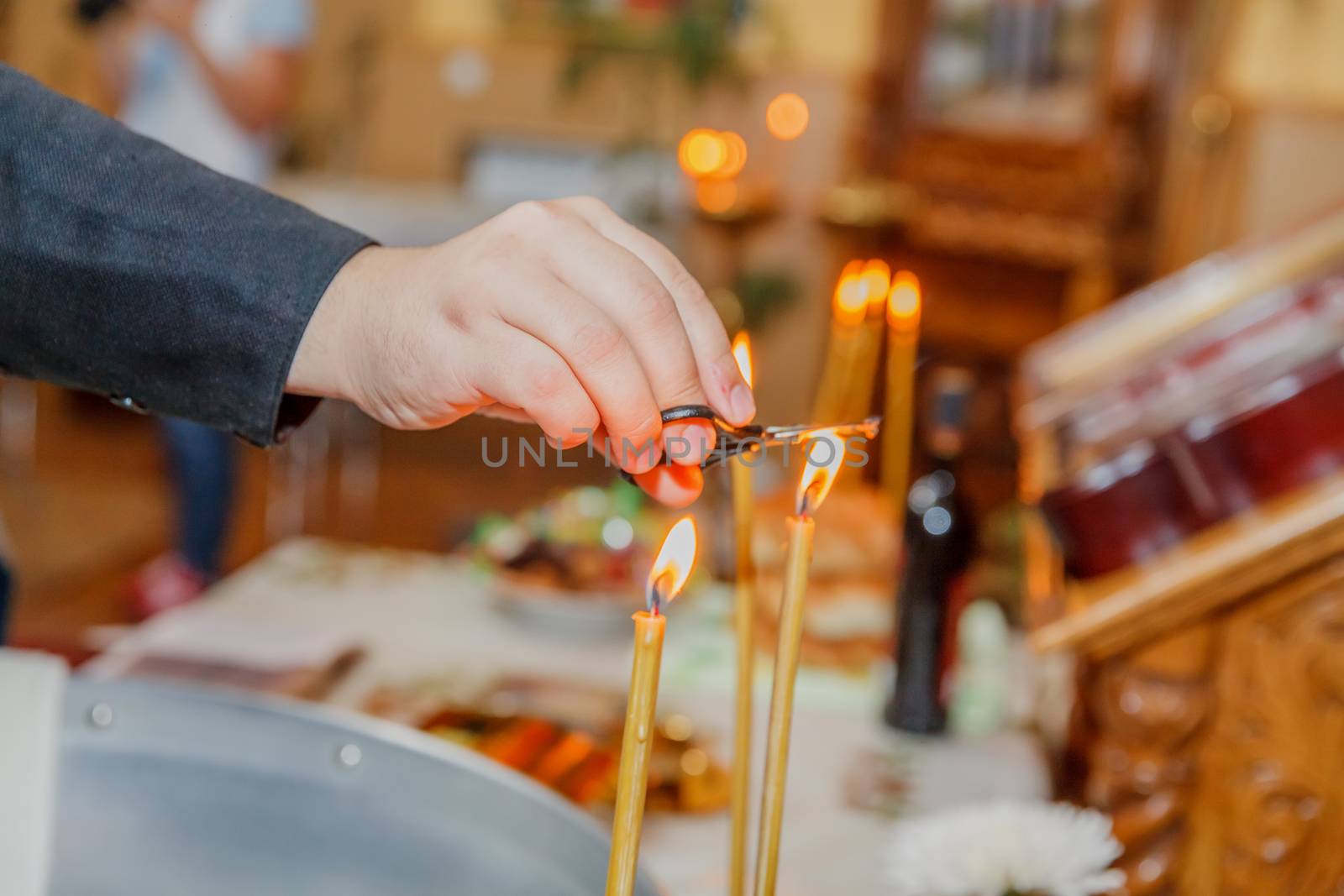 Priest hand burning hair in candle light at orthodox church