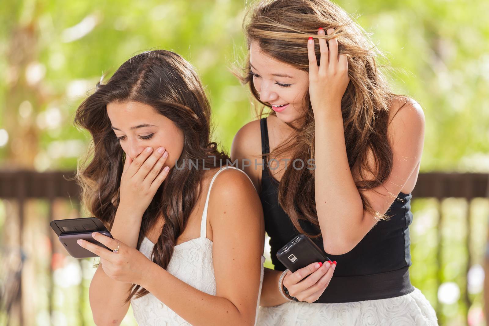 Two Expressive Mixed Race Girlfriends Using Their Smart Cell Phones Outdoors