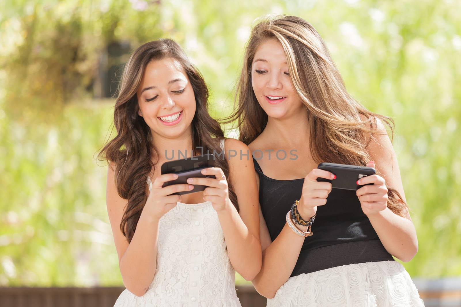 Two Expressive Mixed Race Girlfriends Using Their Smart Cell Phones Outdoors