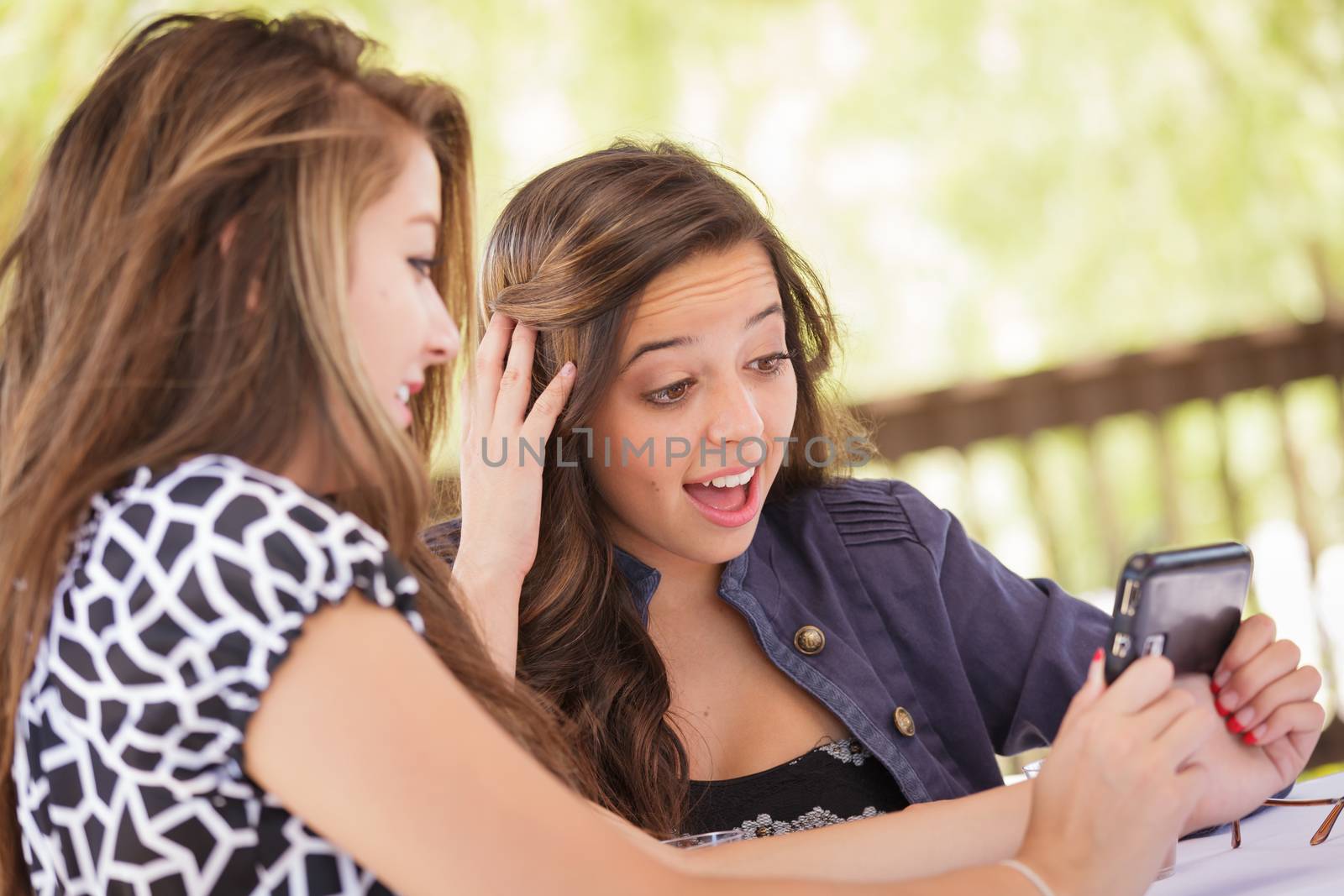 Expressive Young Adult Girlfriends Using Their Smart Cell Phone Outdoors