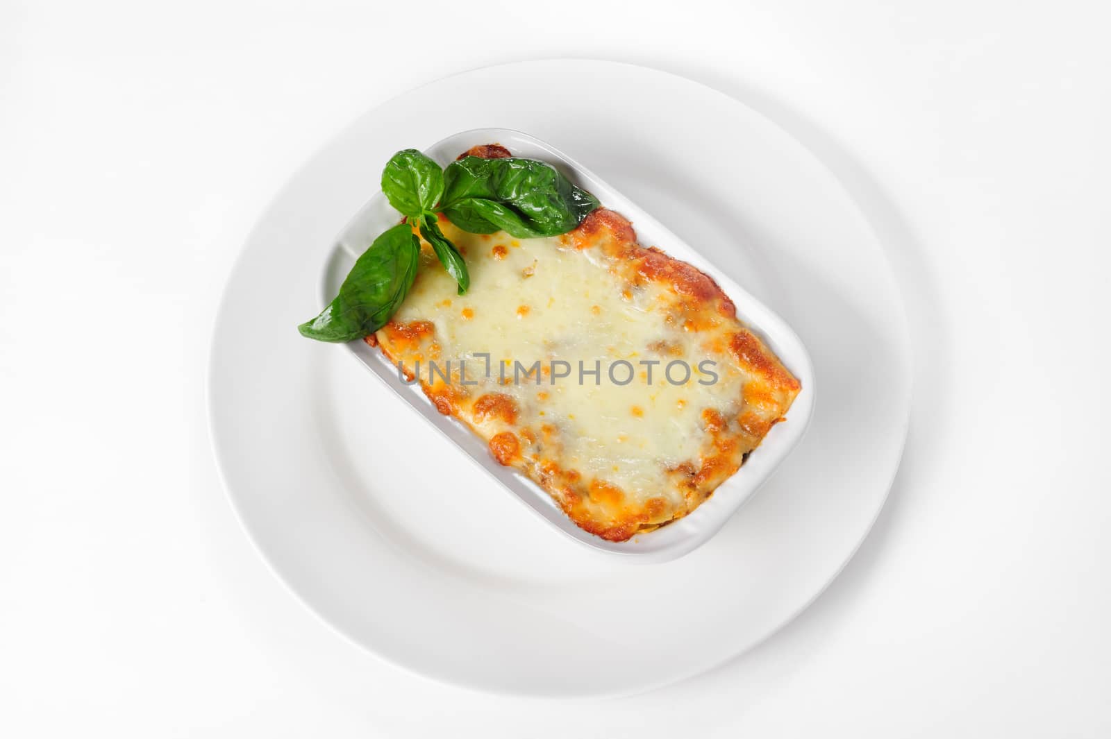 Fresh hot lasagna in white plate on natural white background