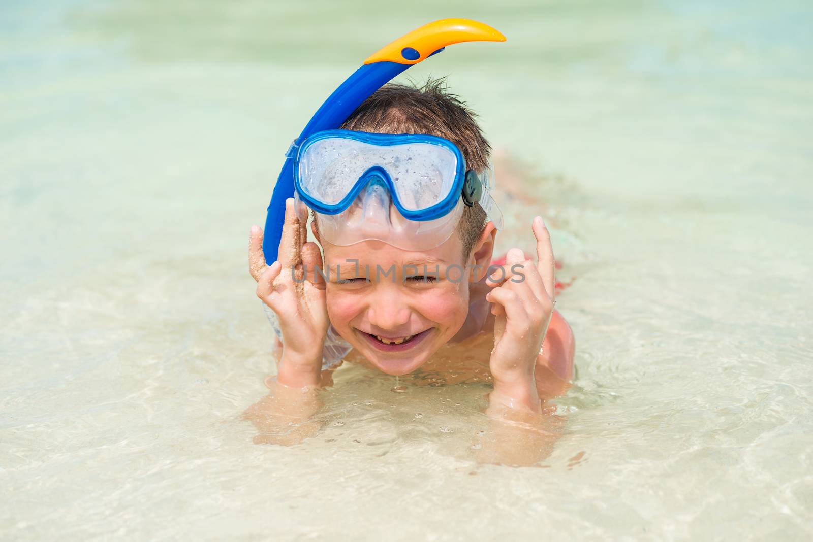 smiling boy 7 years in a snorkeling mask in the sea