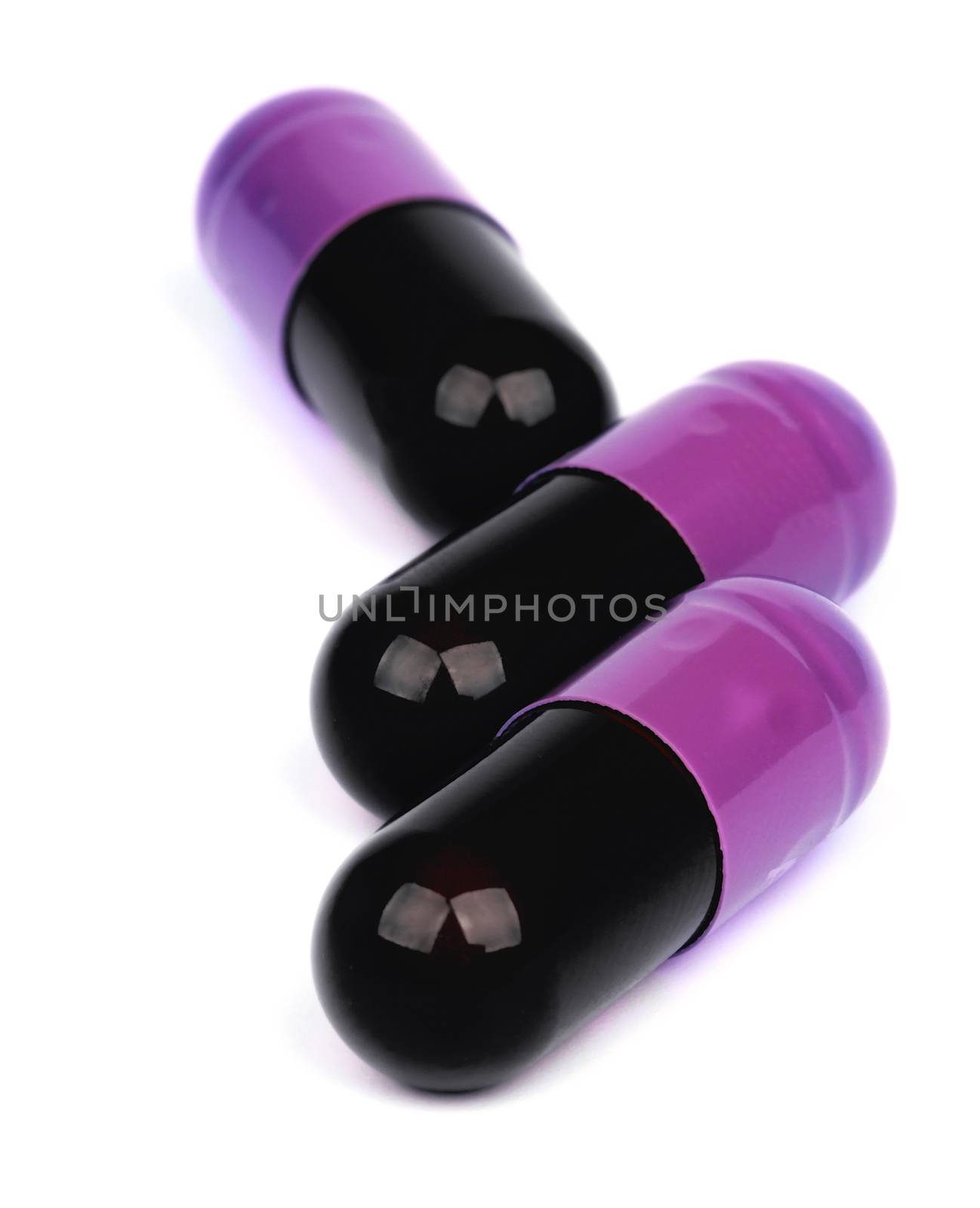 Three Black and Pink Vitamin Pill Capsules Isolated on White background