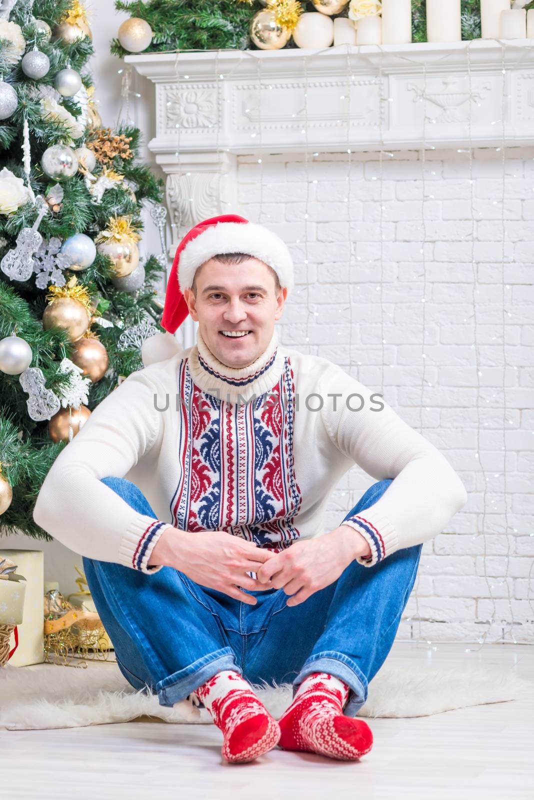 nice man in a sweater and New Year's socks sitting near a Christmas tree