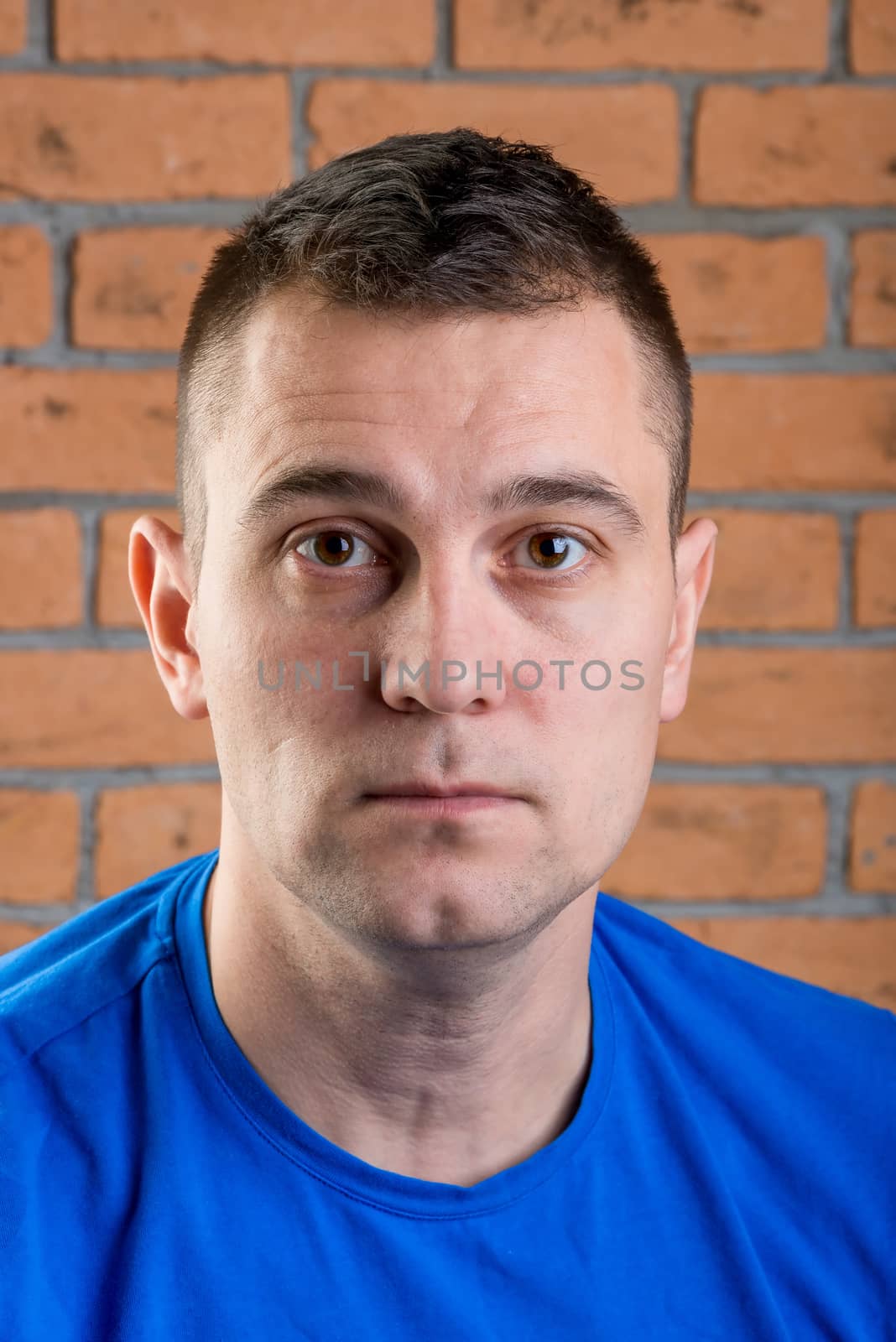 man brunet in blue t-shirt on brick wall background