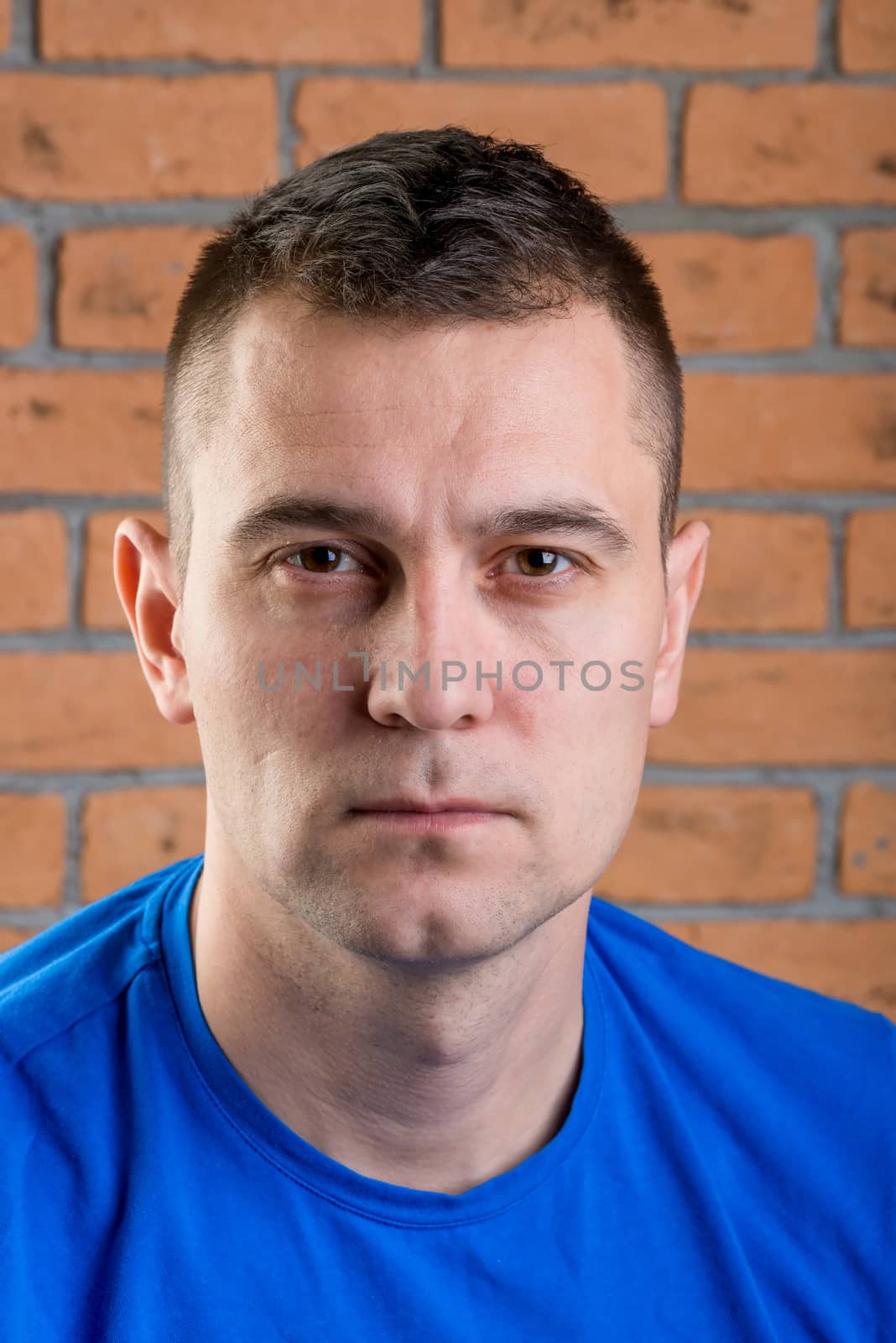 portrait of brutal brunette in blue t-shirt on brick wall background