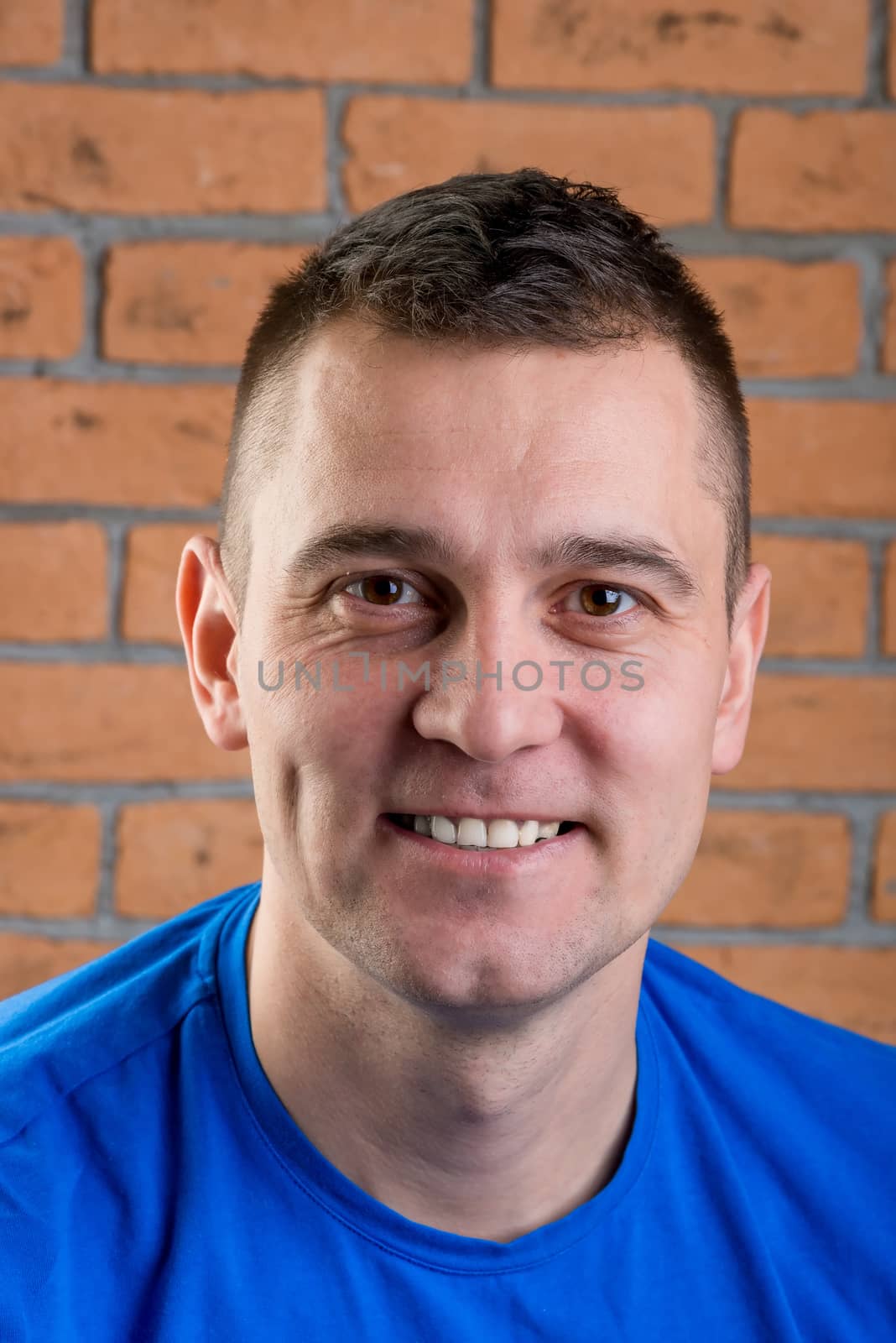 happy brunette in blue t-shirt on brick wall background