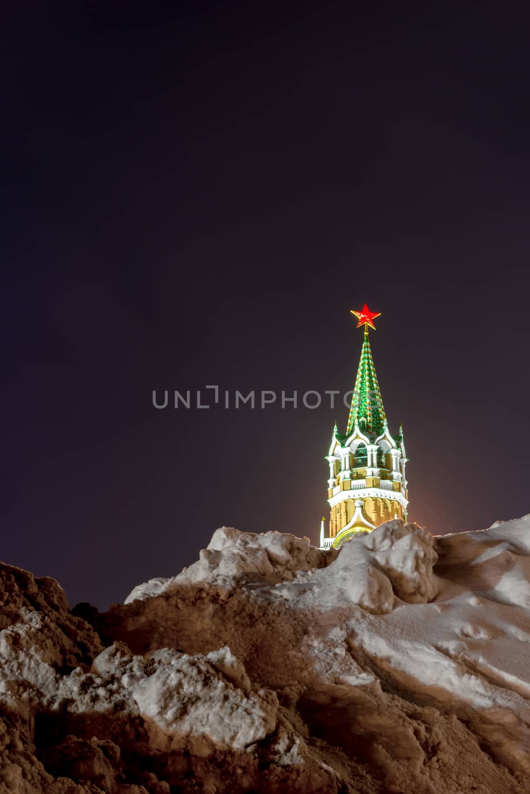 a pile of snow and a view of the Kremlin tower in Moscow on a winter evening