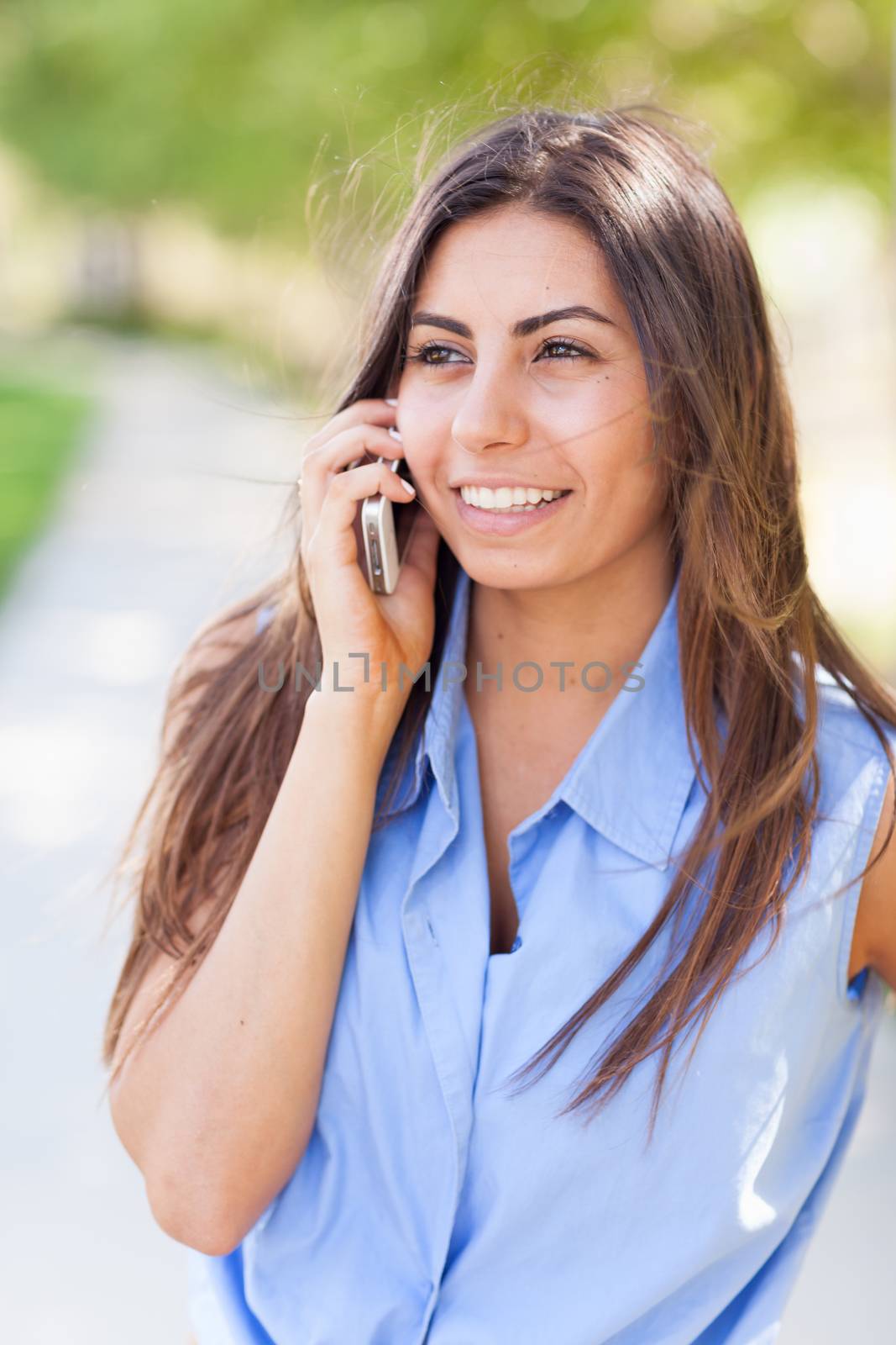 Beautiful Young Ethnic Woman Talking on Her Smartphone Outside.