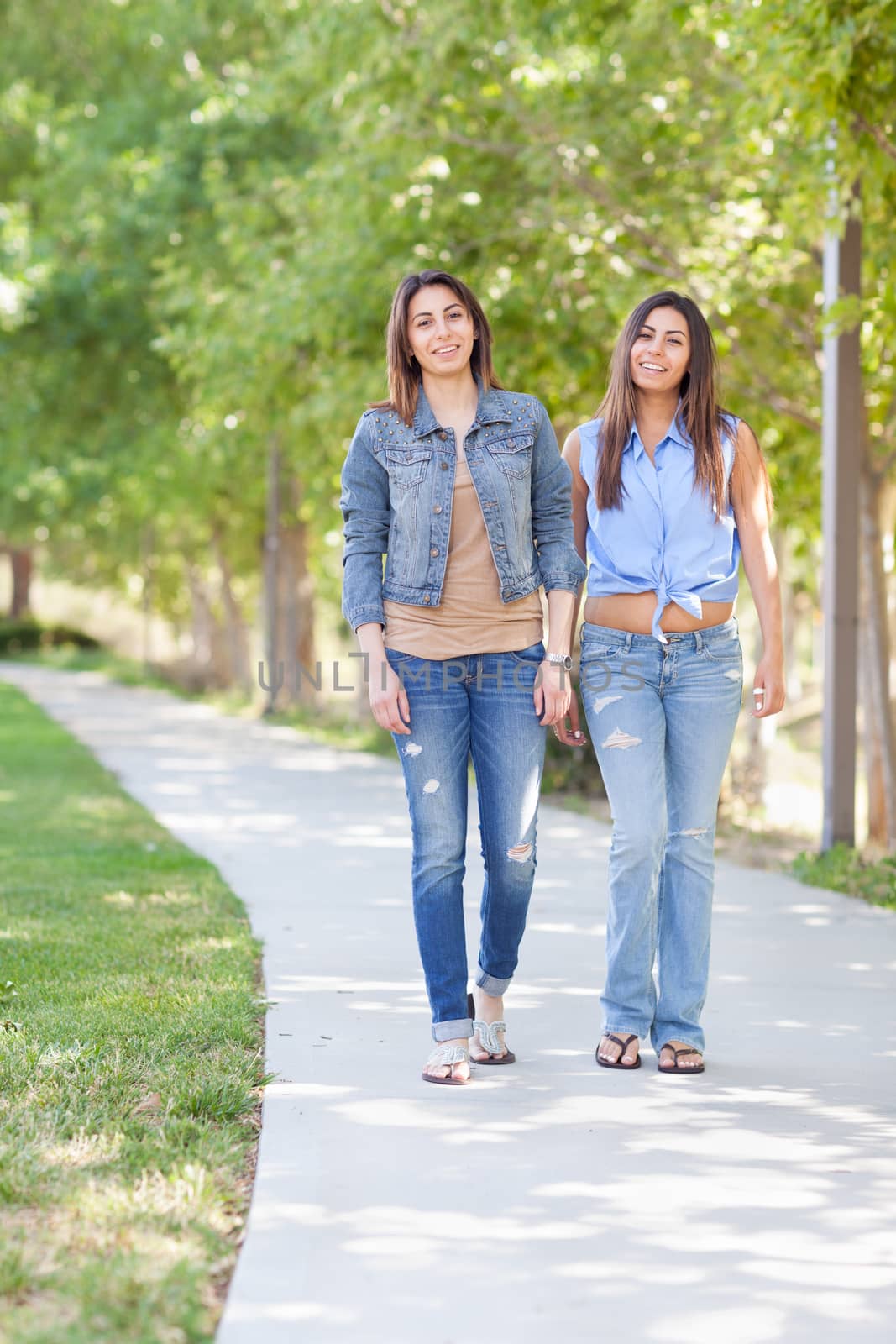 Two Beautiful Ethnic Twin Sisters Walking Outdoors. by Feverpitched