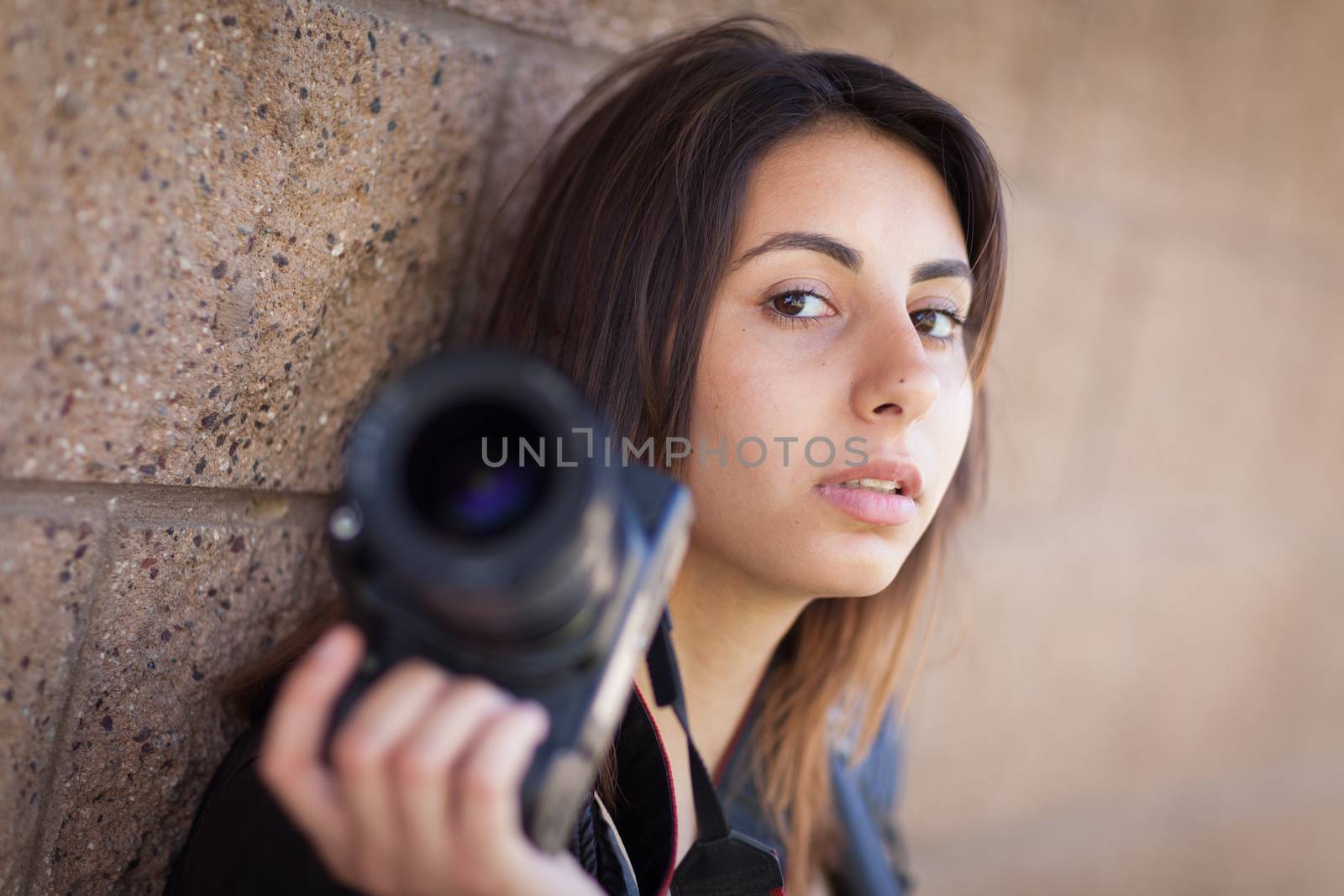 Young Adult Ethnic Female Photographer Against Wall Holding Camera.