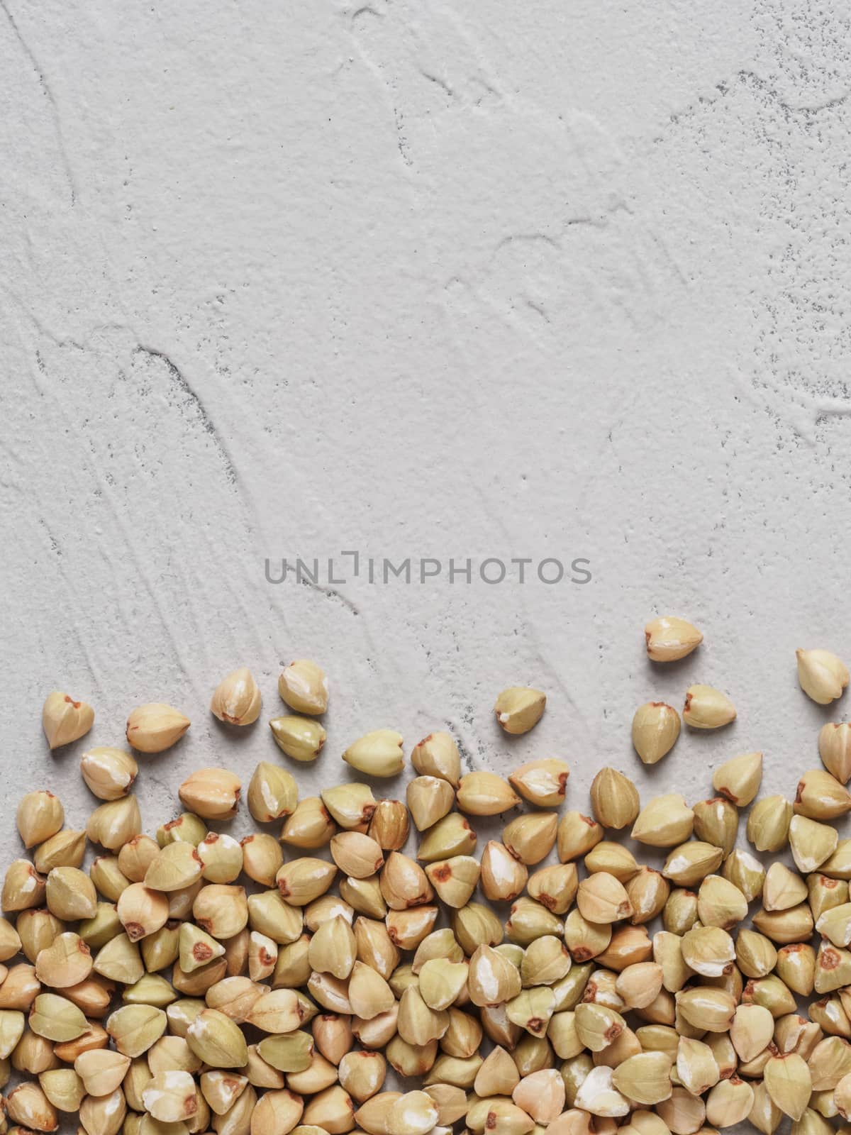 Raw green buckwheat on gray concrete background Healthy food and diet concept. Top view or flat lay. Vertical.