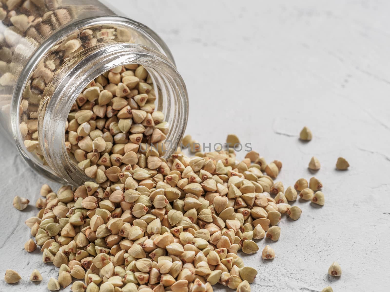 Raw green buckwheat in bank on gray concrete background. Healthy food and diet concept