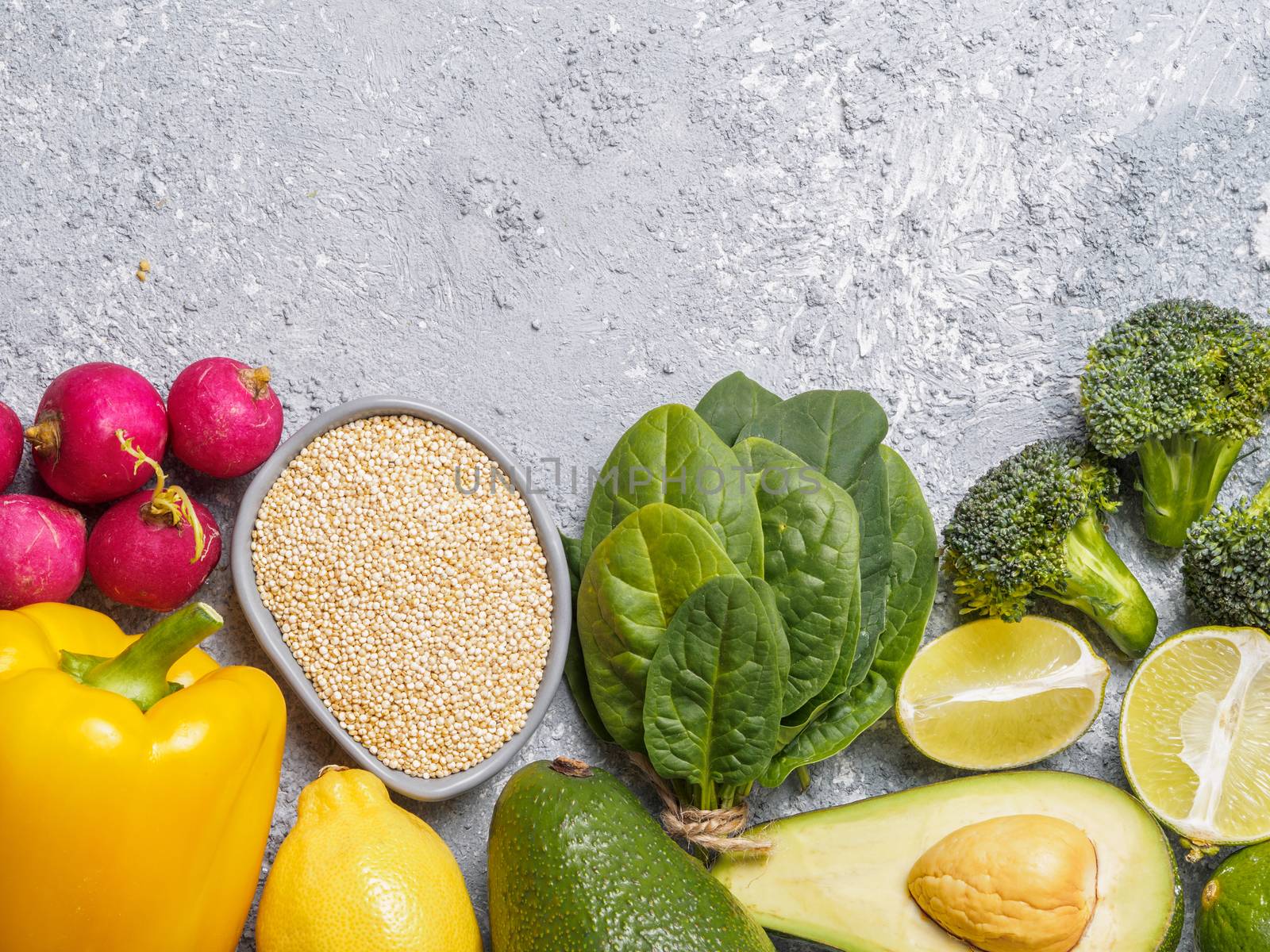 Quinoa and vegetables on gray concrete background. Vegan food ingredients. Colorful food background. Copy space. Top view or flat lay.